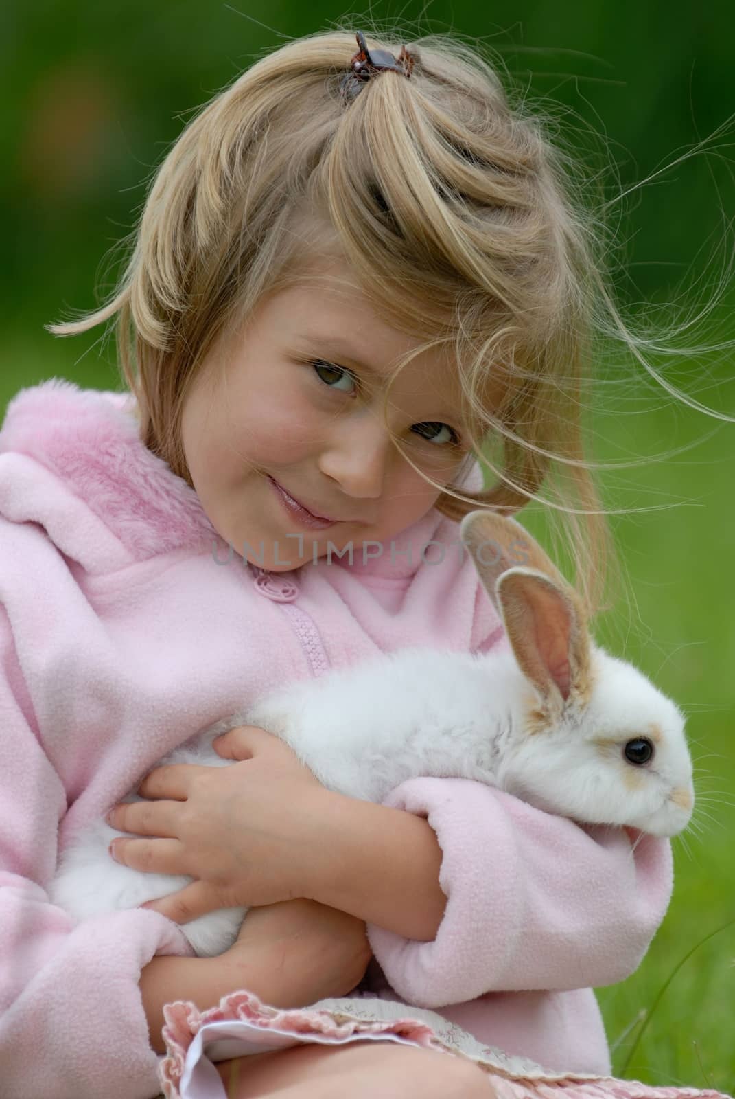 Cute small girl in pink is caring little white rabbit. by kertis