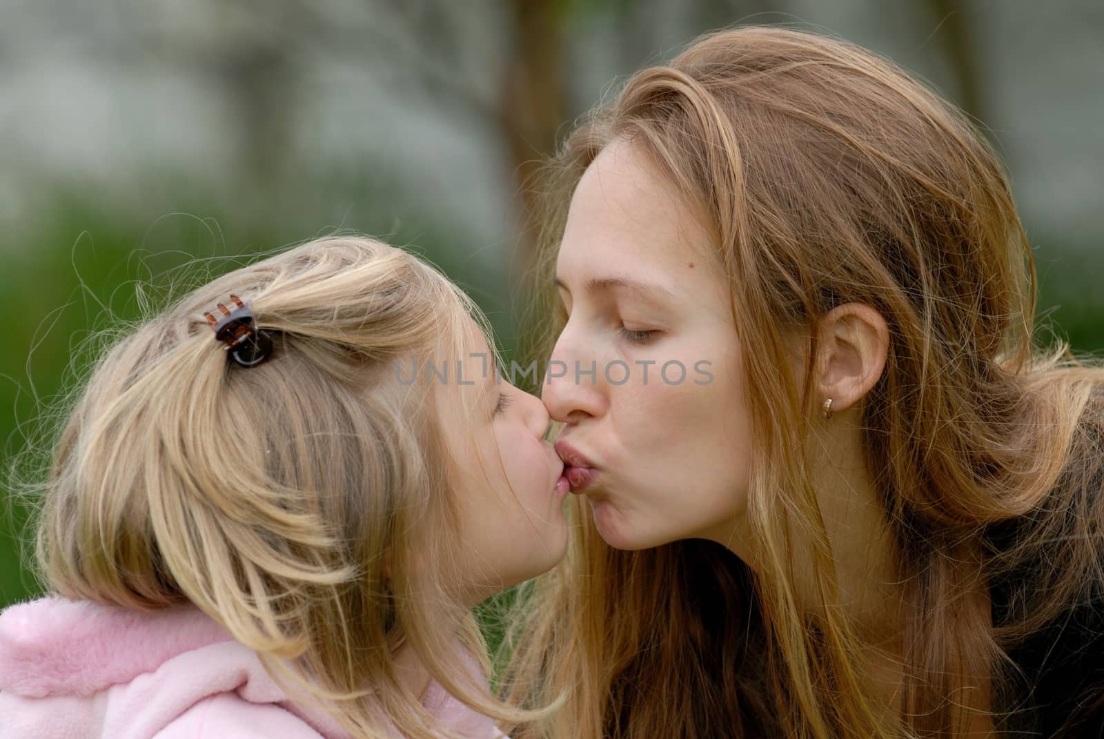 Blond girl and long haired mom are kissing. each other. Portarait by kertis