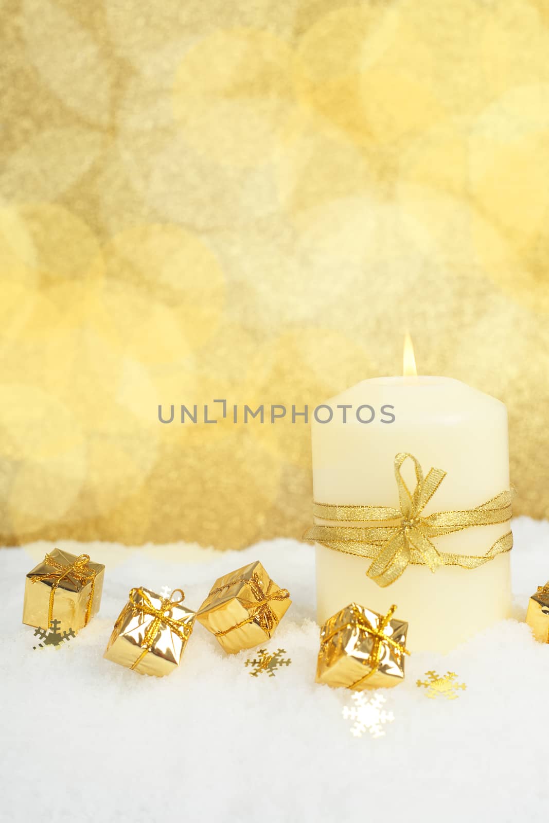 Christmas candle on snow on golden bokeh background