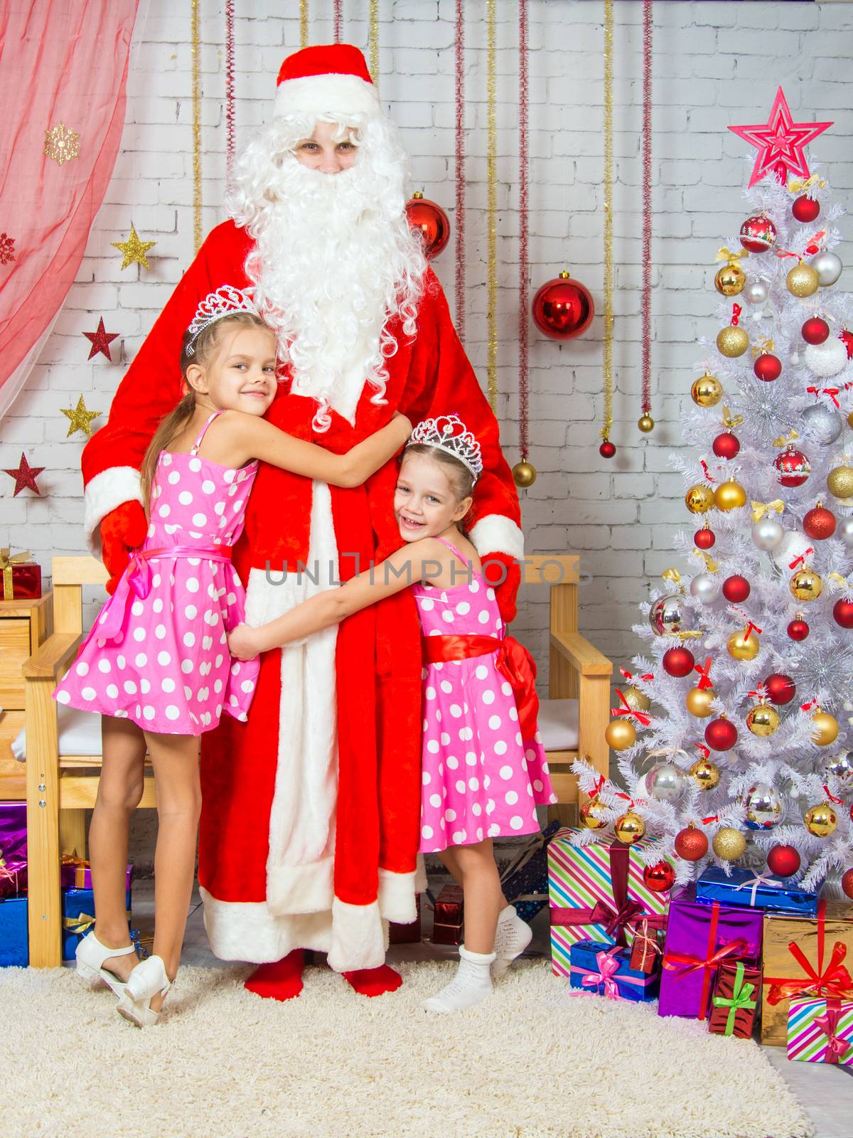 Santa Claus congratulates two girls sisters a Happy New Year and Merry Christmas in the home New Years interior
