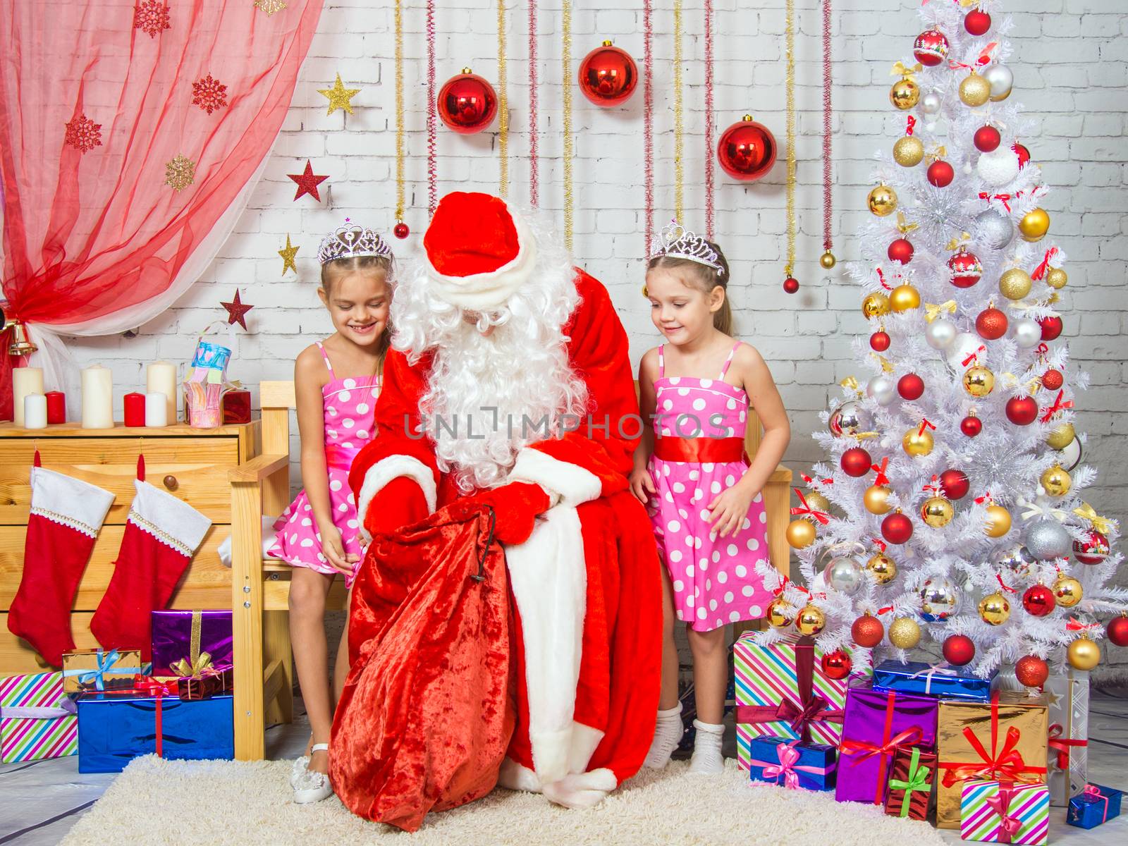 Santa Claus congratulates two girls sisters a Happy New Year and Merry Christmas in the home New Years interior