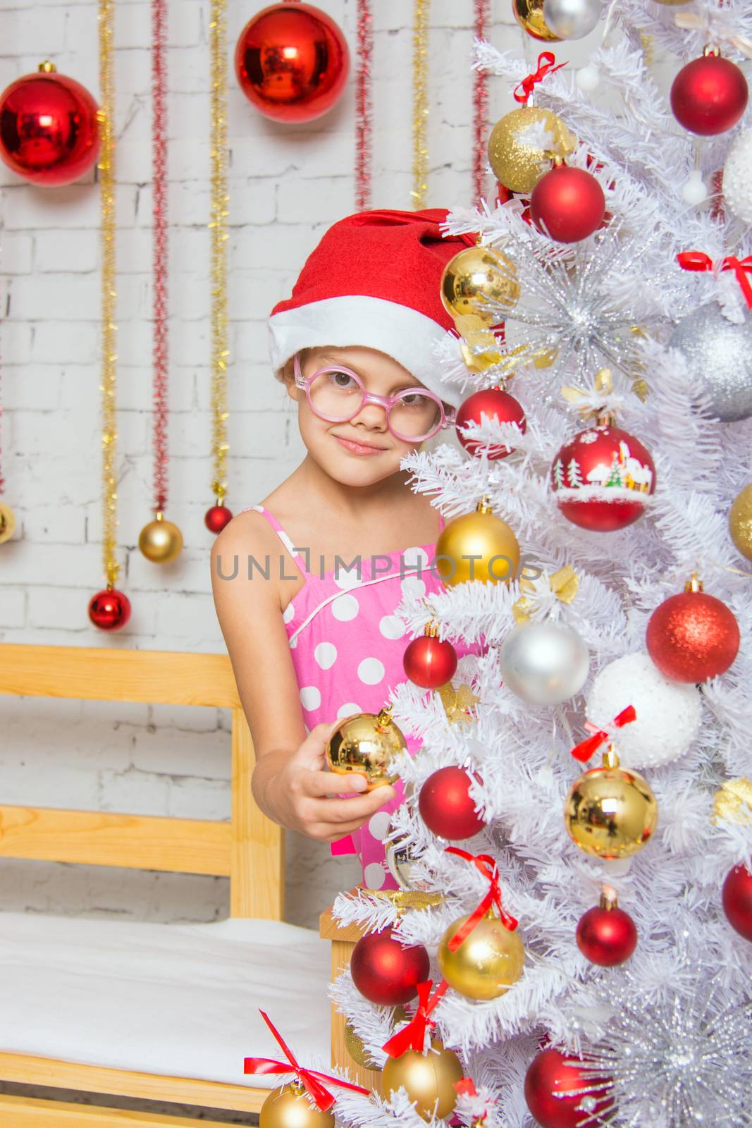 Six year old girl hangs balls on the Christmas tree Christmas snow