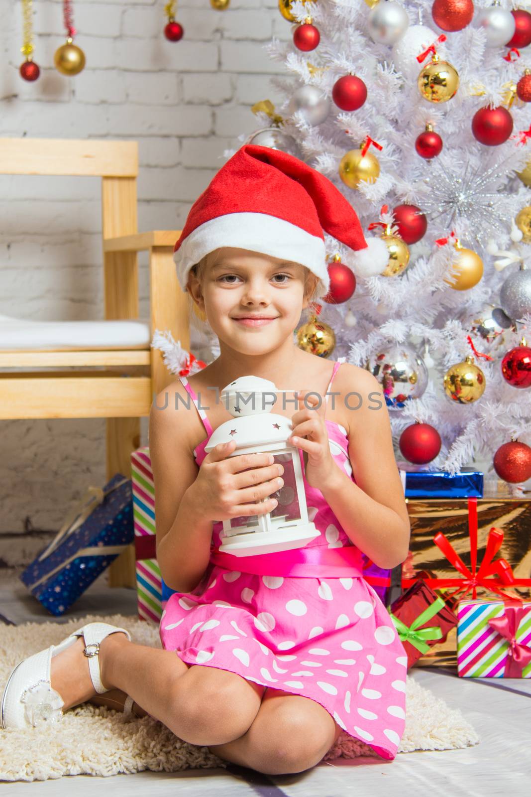 Six year old girl sitting on a mat at a snowy Christmas trees