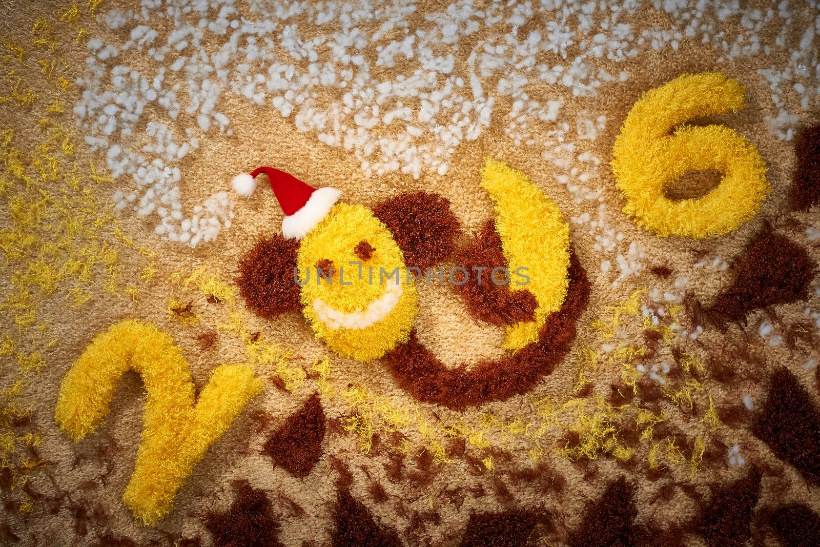New Year 2016. Christmas.Funny monkey in Santa hat with banana. Happy vivid festive still life. Yellow fabric digits handmade. Playful fluffy party decoration.Shaggy unusual holiday card, copyspace
