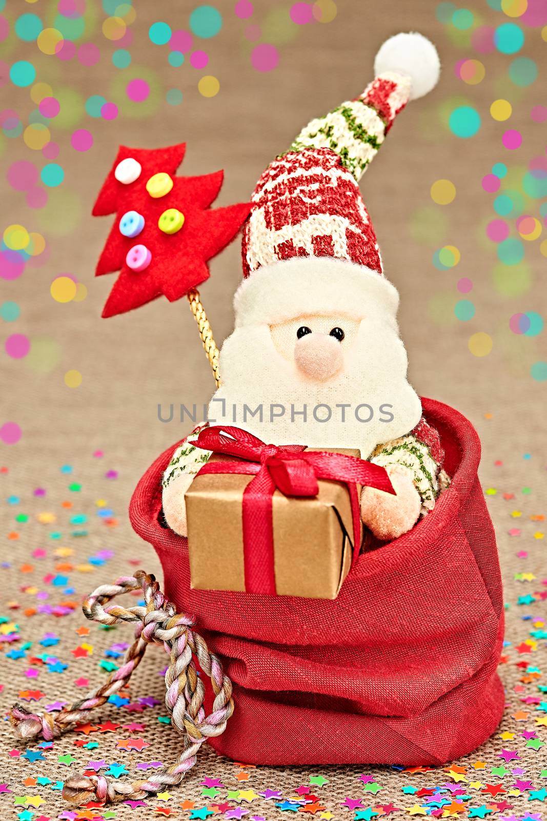 New Year 2016. Merry Christmas. Cute Santa Claus with Christmas tree and big sack of presents, handmade on red, bokeh. Happy cheerful traditional holiday. Vivid greeting card, multicolored, copyspace