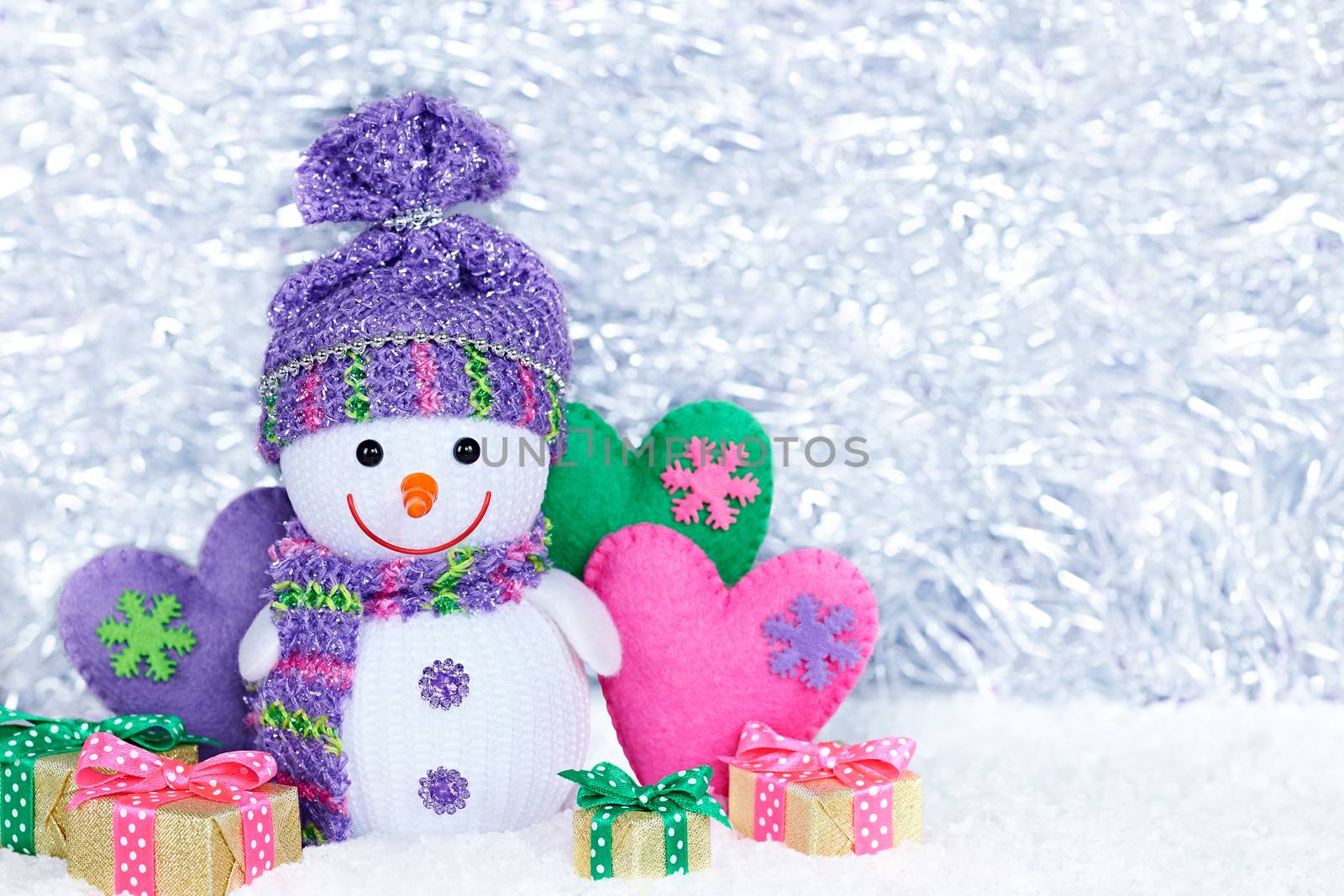 New Year 2016. Happy Snowman on snow. Party decoration. Cheerful fun winter holiday on silver background, copyspace. Snowman with multicolored handmade hearts and gift boxes , love concept