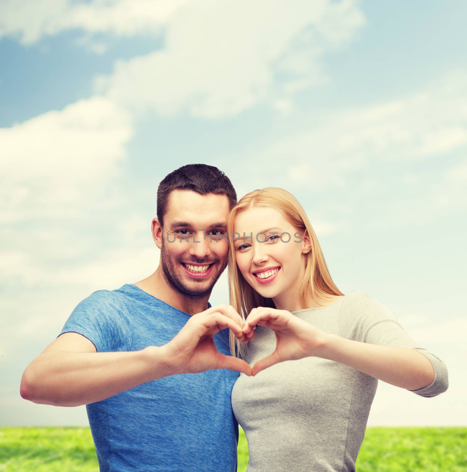 smiling couple showing heart with hands by dolgachov