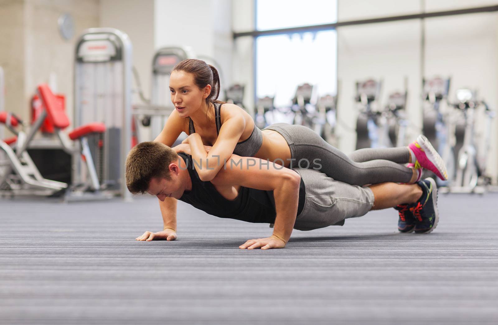 fitness, sport, training, teamwork and lifestyle concept - smiling couple doing push-ups in the gym