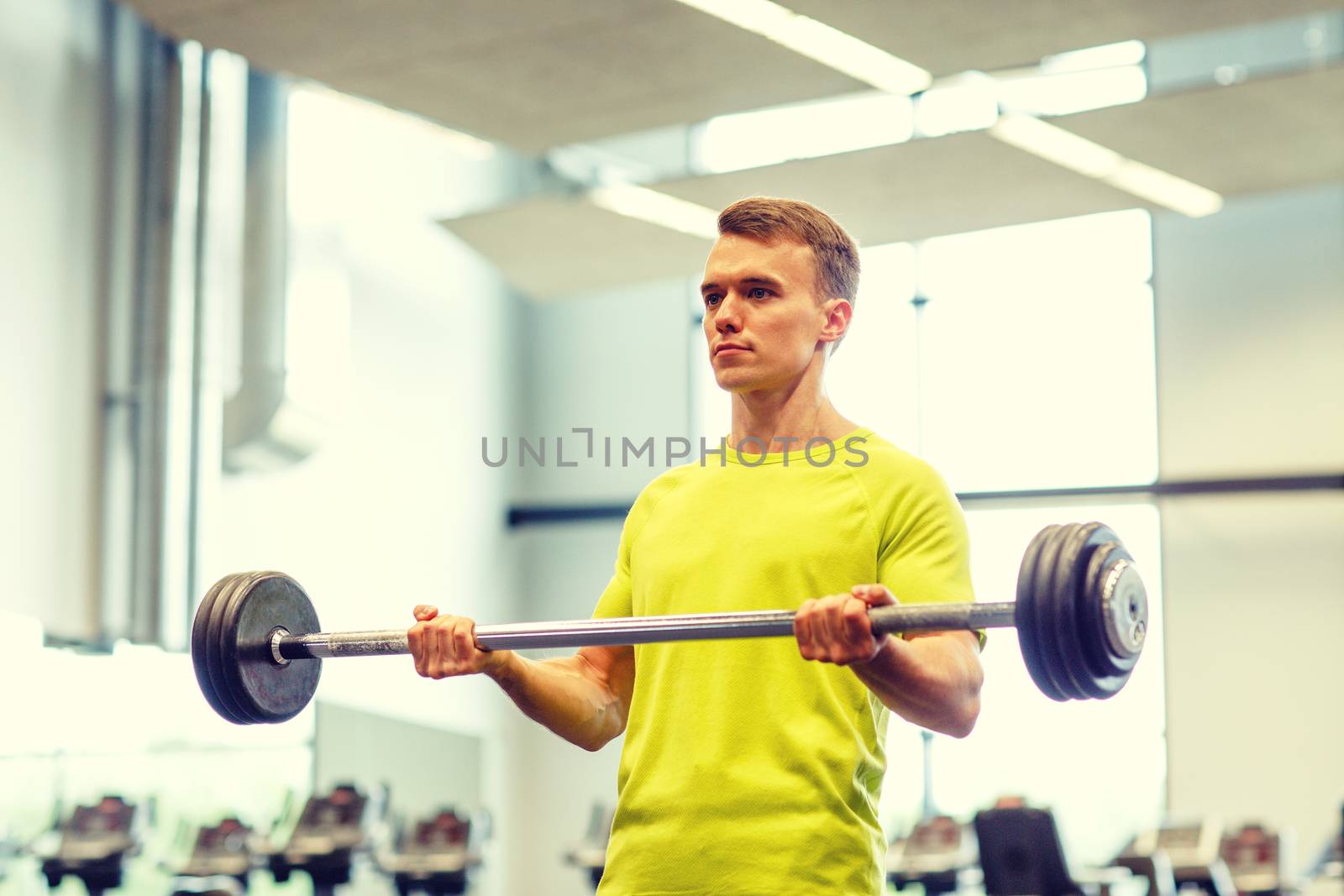 man doing exercise with barbell in gym by dolgachov