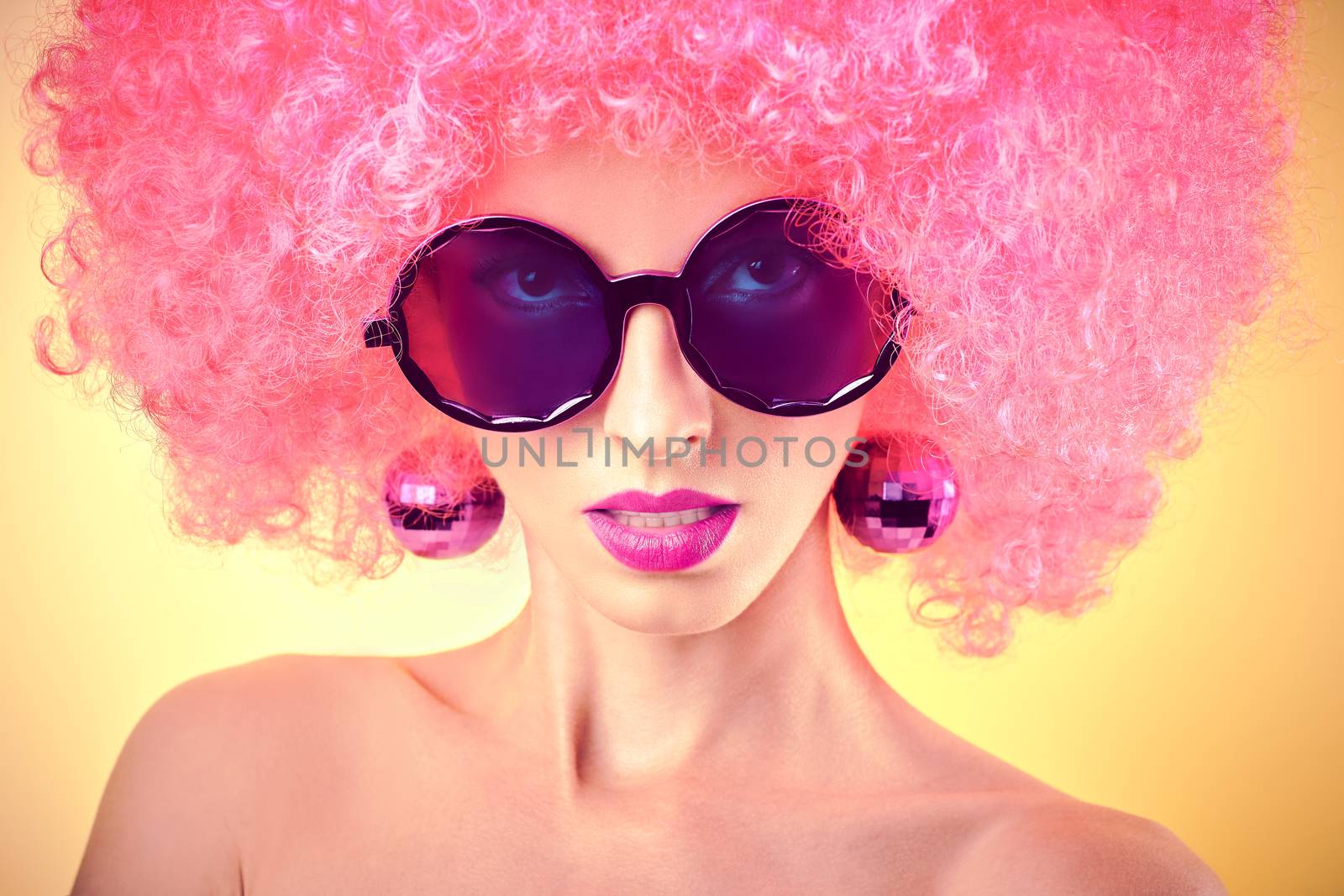 Fashion portrait of sexy nude beauty woman, unusual creative people. Vivid party provocative attractive girl in stylish sunglasses. Curly hipster girl, trendy afro hairstyle on yellow, copyspace. 