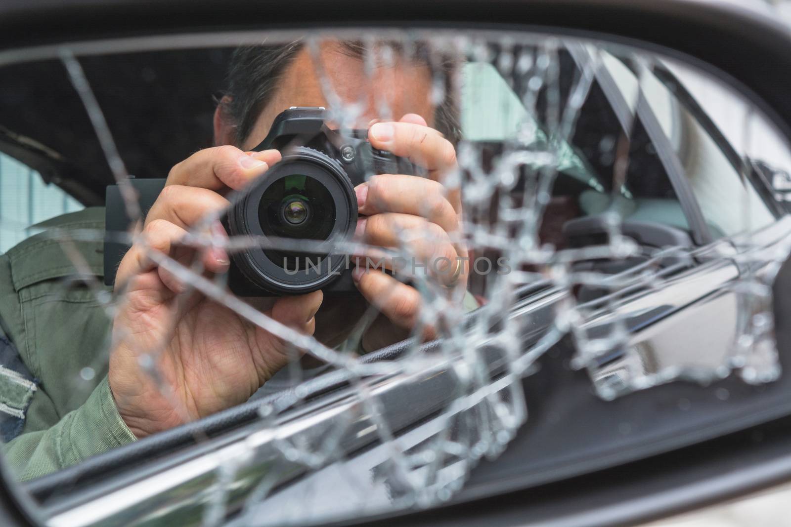 Mirror image of a photographer in the broken car mirror