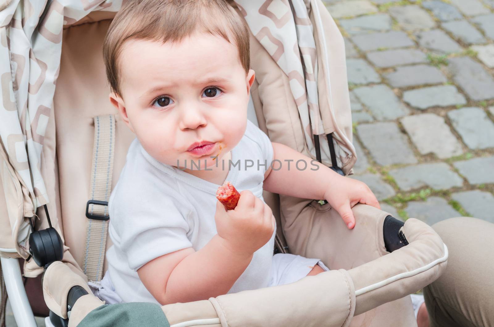 Child in stroller eating a sausage by JFsPic