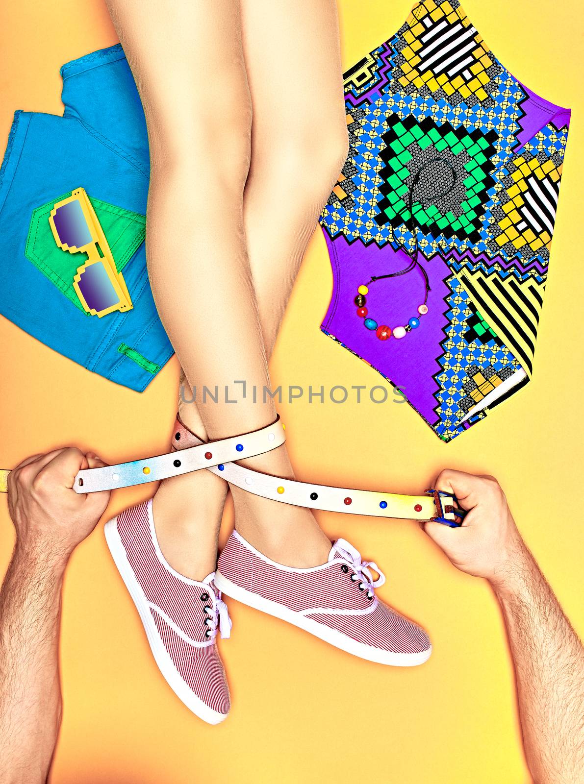 Fashion clothes stylish set, accessories, womans sexy legs, people. Hipster girl creative look in trendy gumshoes, top, shorts, sunglasses. Mans hands holding belt. Vivid youth style, yellow,copyspace
