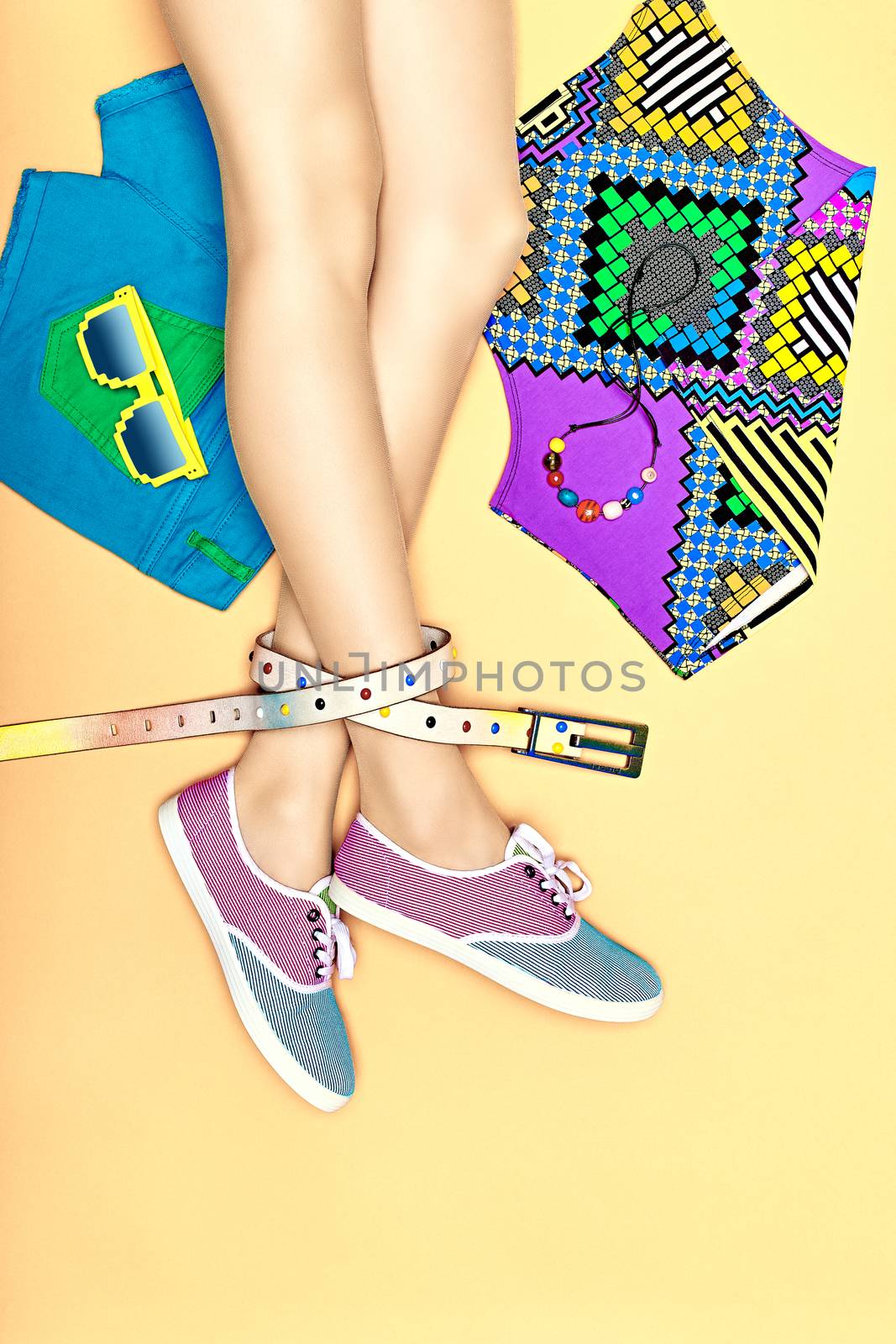 Fashion clothes stylish set, accessories, womans sexy legs, people. Hipster girl creative look in trendy gumshoes, top, shorts, sunglasses, belt. Unusual vivid youth style on yellow, copyspace