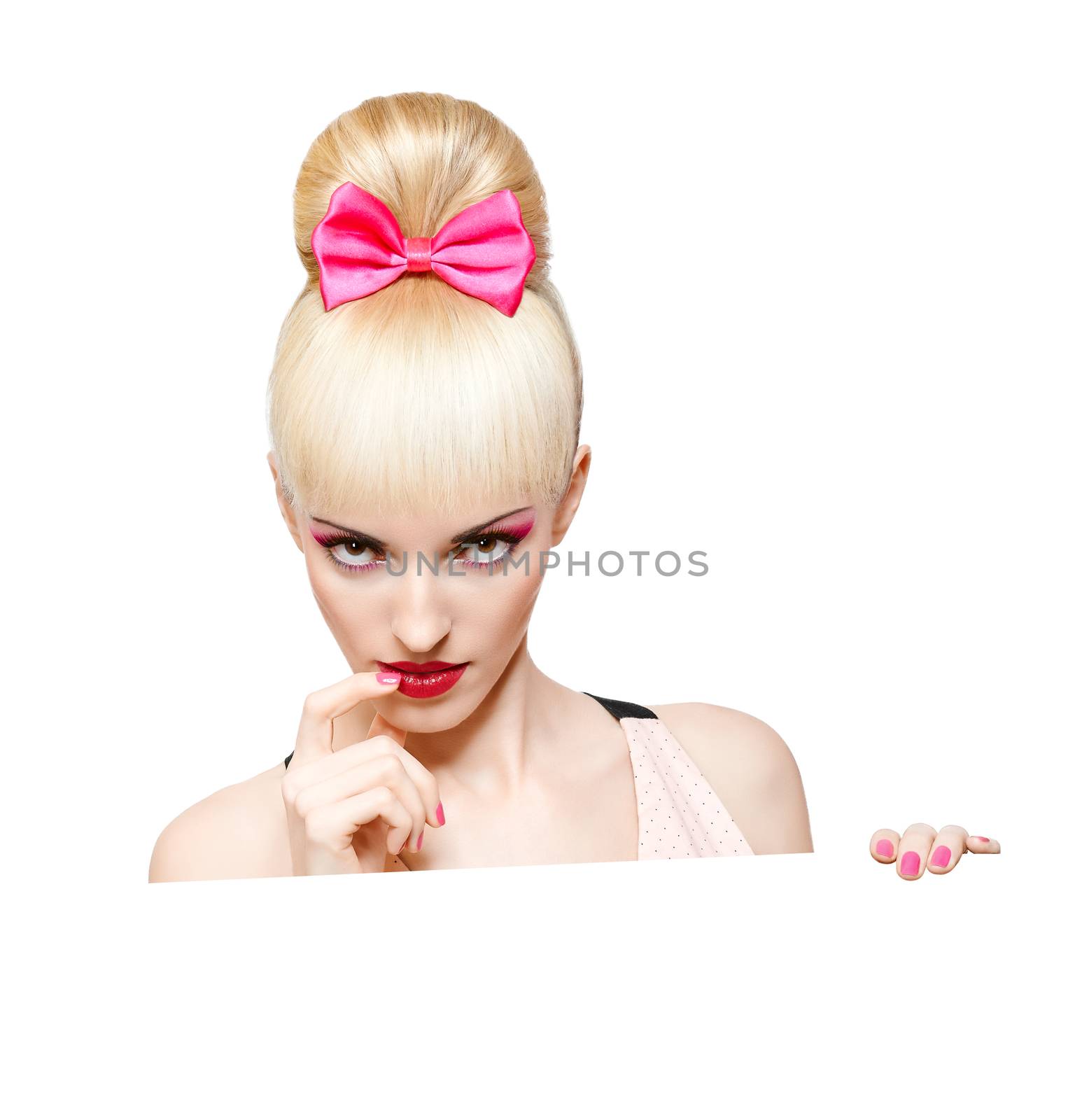 Portrait  of beautiful woman peeking over edge of billboard, banner sign isolated on white. Confident blonde girl with Pinup hairstyle, fringe and pink bow, make up. Face closeup. Billboard. 