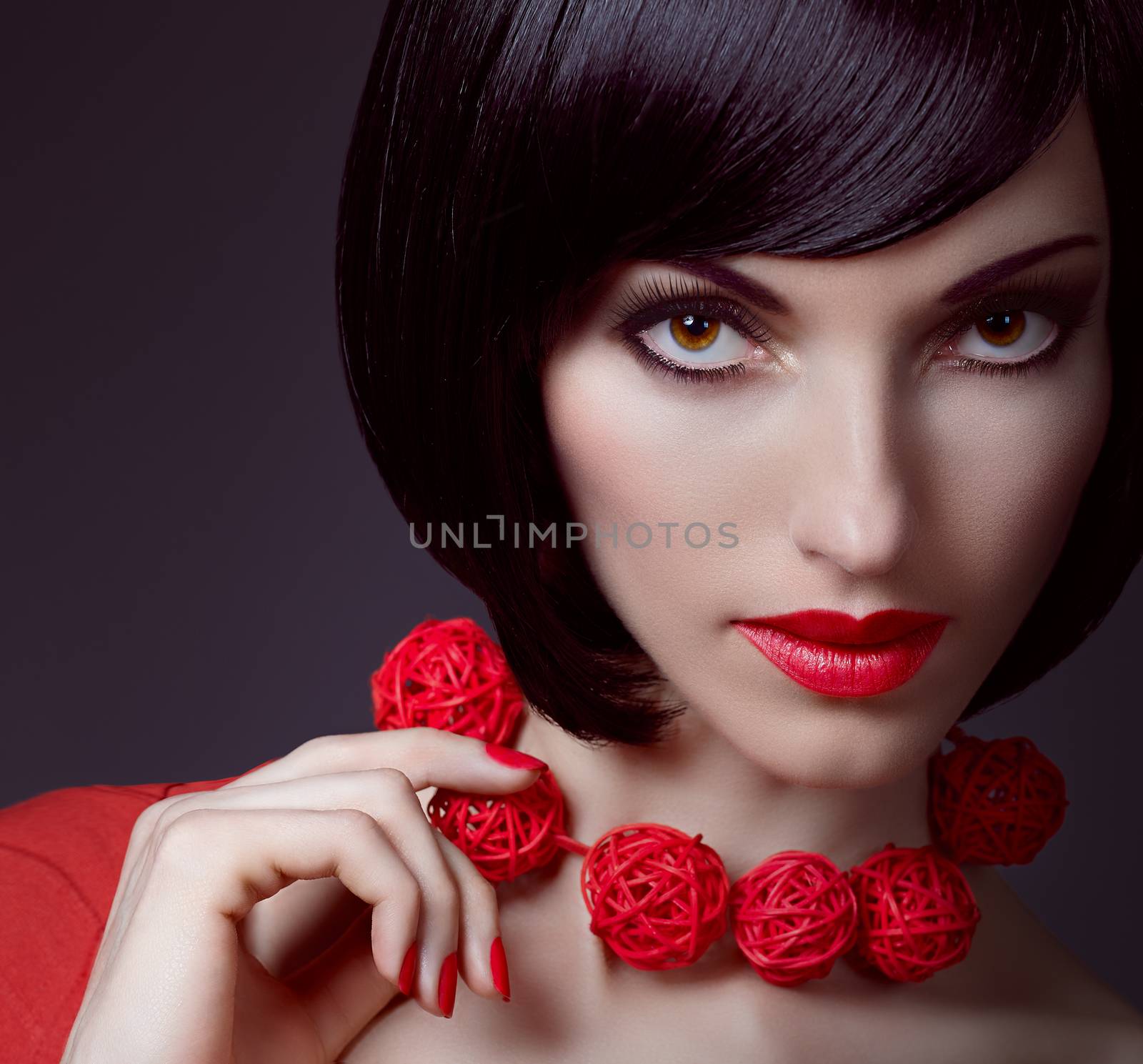 Fashion beauty portrait of sexy brunette woman, silky bob hairstyle on dark. Sensual lady with stylish necklace mysteriously looks. Brown-eyed girl, luxury makeup, red lips. People face closeup