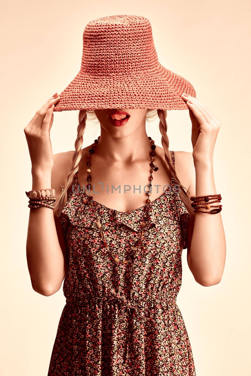 Beauty  playful boho slim woman in orange hat licking lips, romantic style, people. Hippie young joyful girl with blonde pigtails in floral fashion sundress happy, having fun. Summer look. Toned 