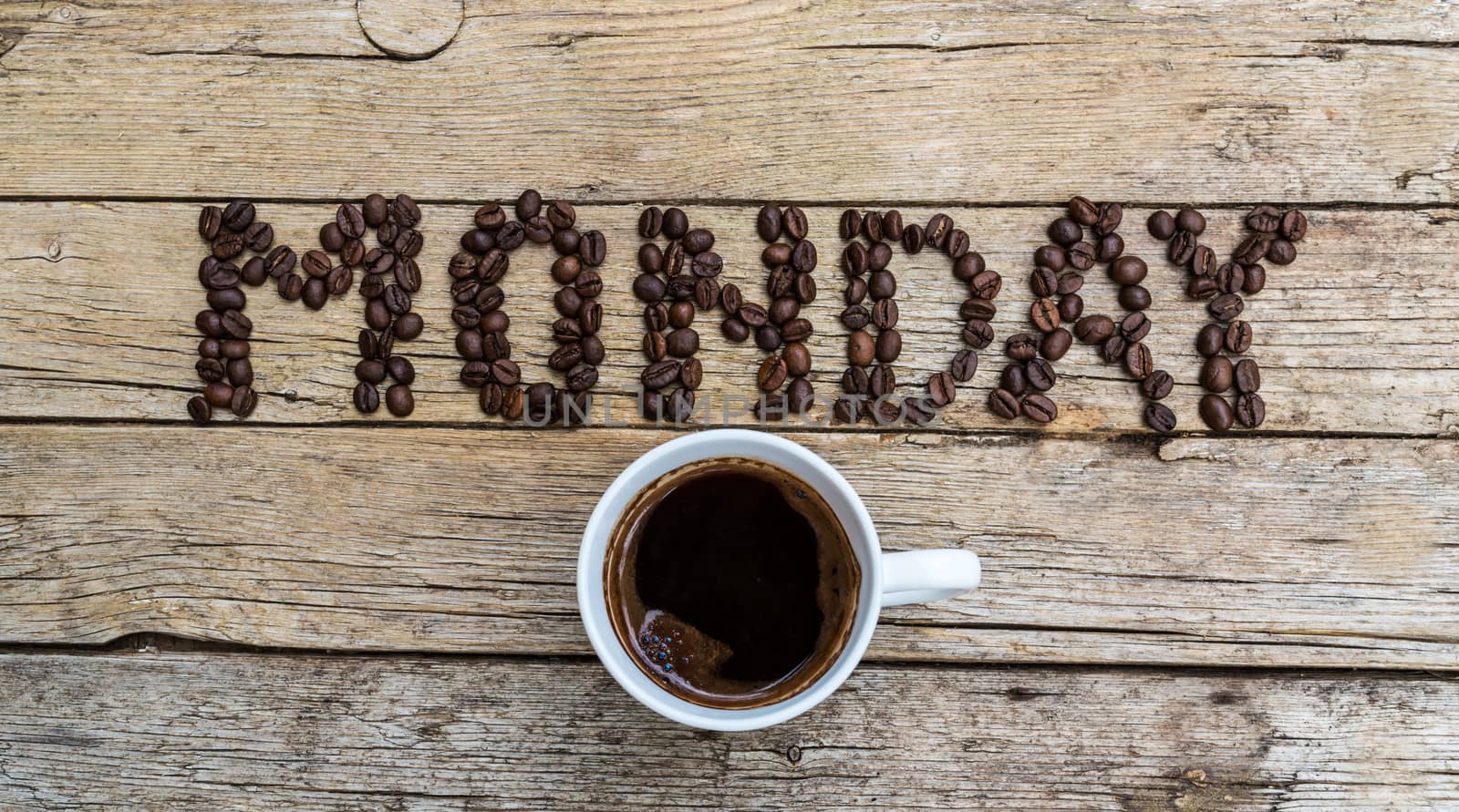 Cup of coffee on wooden background and MONDAY coffee beans 