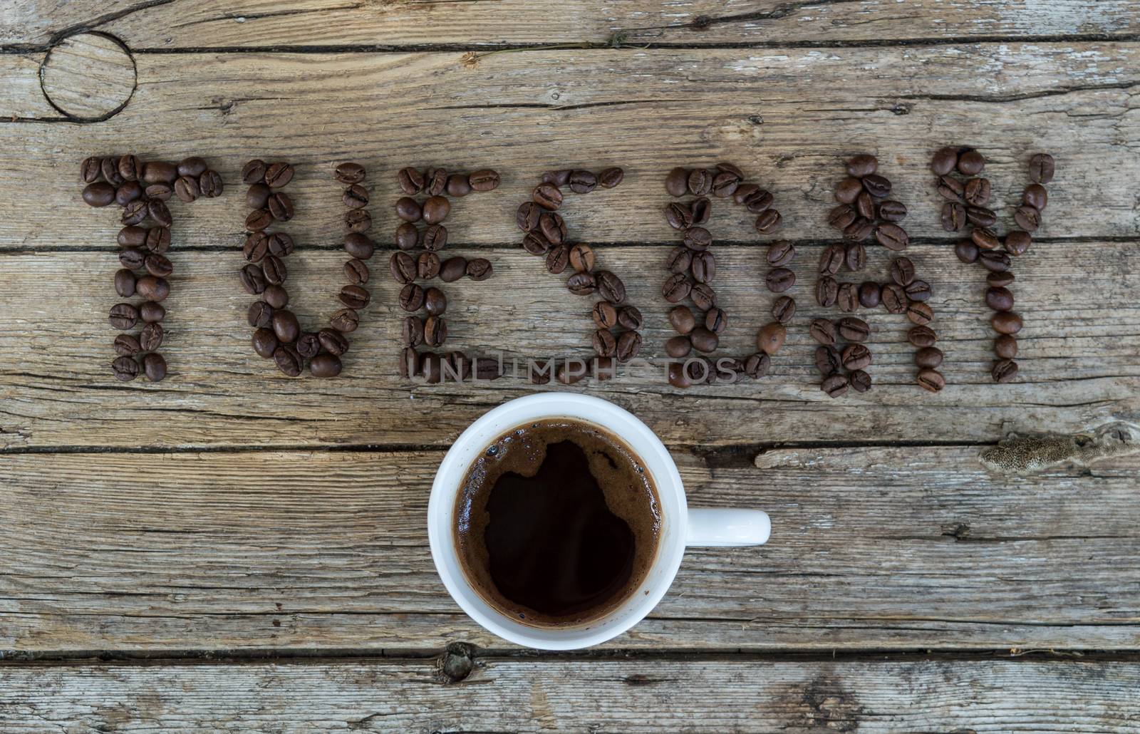Cup of coffee on wooden background and TUESDAY coffee beans 