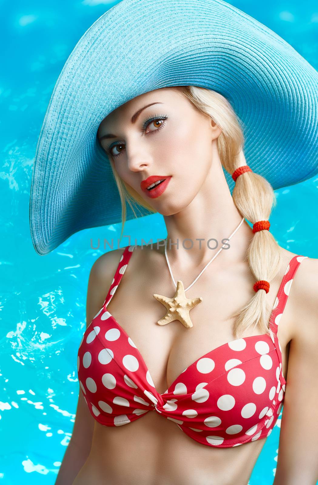 Beautiful woman in red polka dots fashionable swimsuit. PinUp playful sexy girl sensually looks, blue hat. Beach body, slim female figure, people, copyspace. Summer holiday, sea vacation 