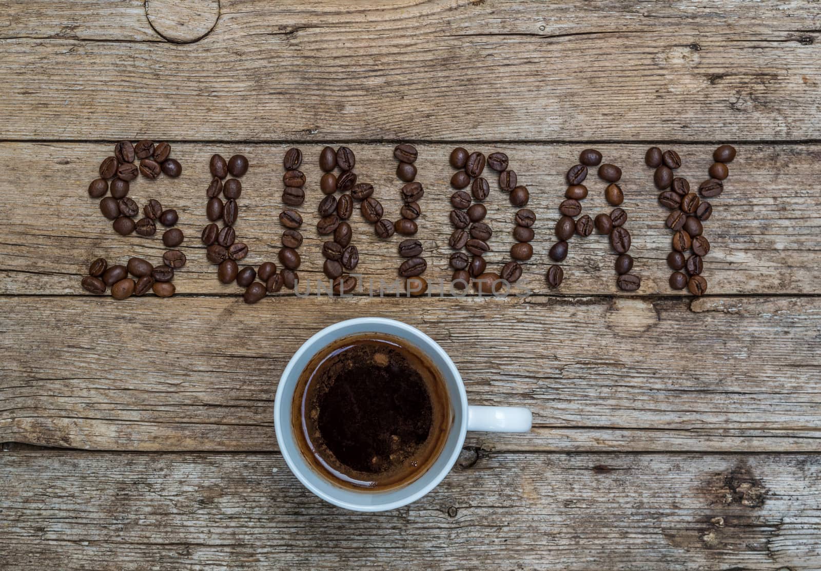 Cup of coffee on wooden background and SUNDAY coffee beans 