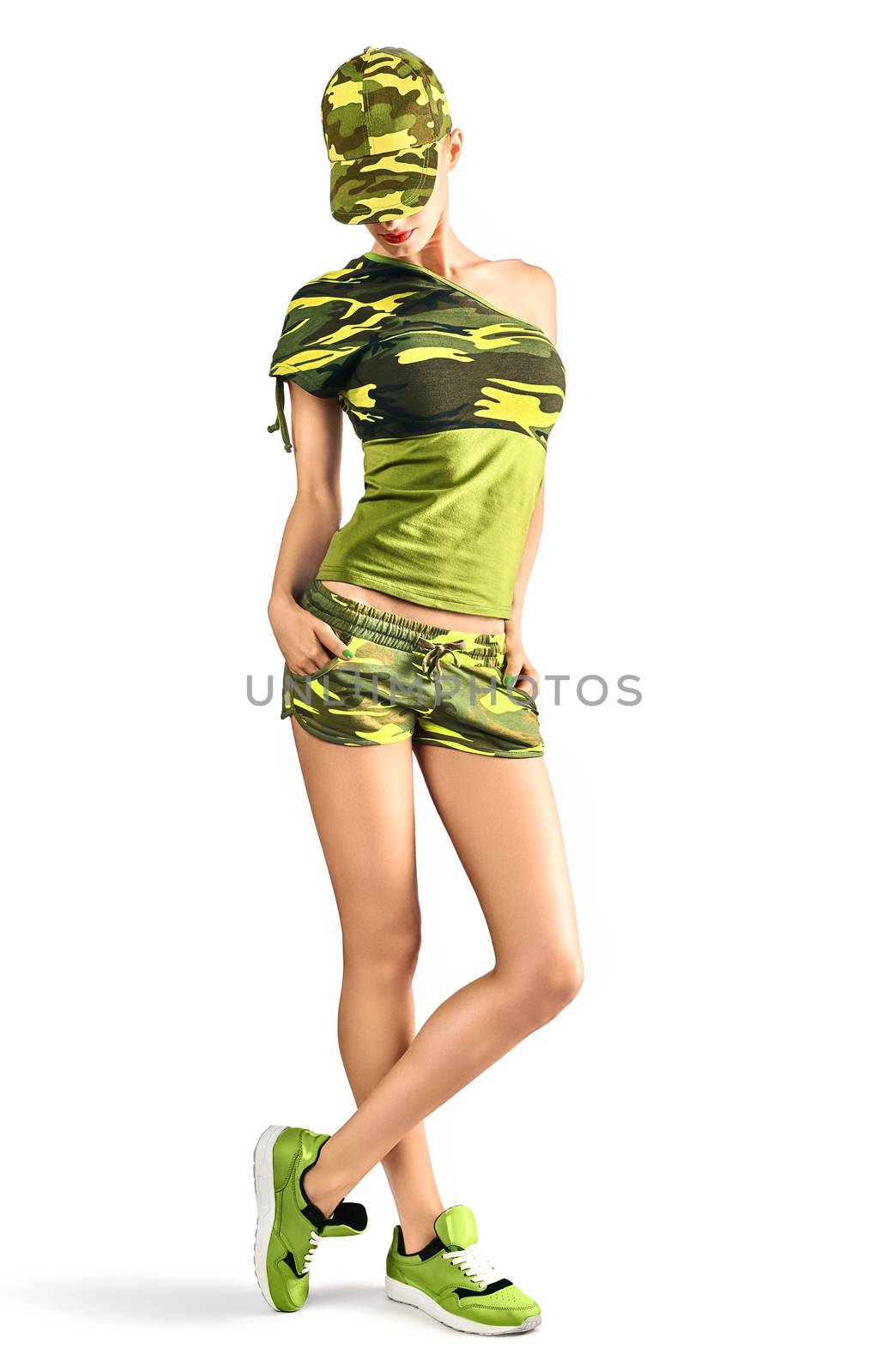 Fashion woman in camouflage clothes. Army beauty sexy military girl looking down with hands in pockets. Stylish playful people, unusual khaki green look, isolated on white. Attractive blond creative 