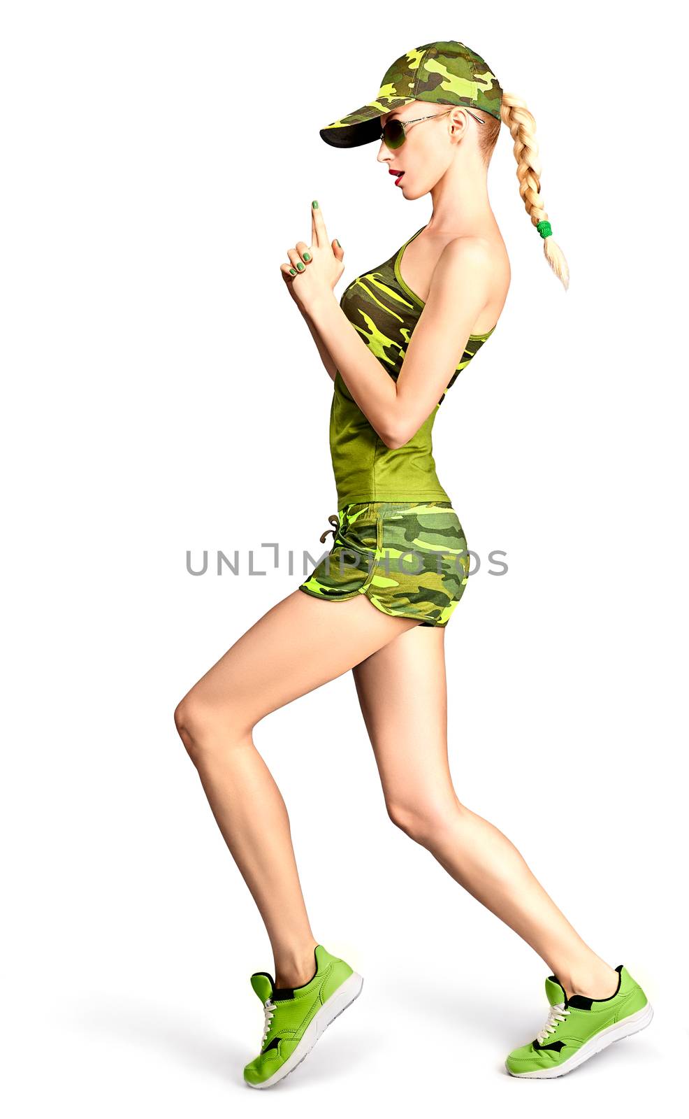 Fashion woman in camouflage clothes. Army beauty sexy military girl doing hands like a gun. Stylish playful people, unusual khaki green look, isolated on white. Attractive blond girl makes gun gesture