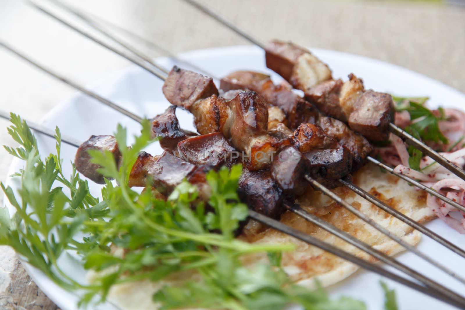 Close up detailed view of grilled delicious liver shish kebab of Turkey served on a white plate with parsley and onion.