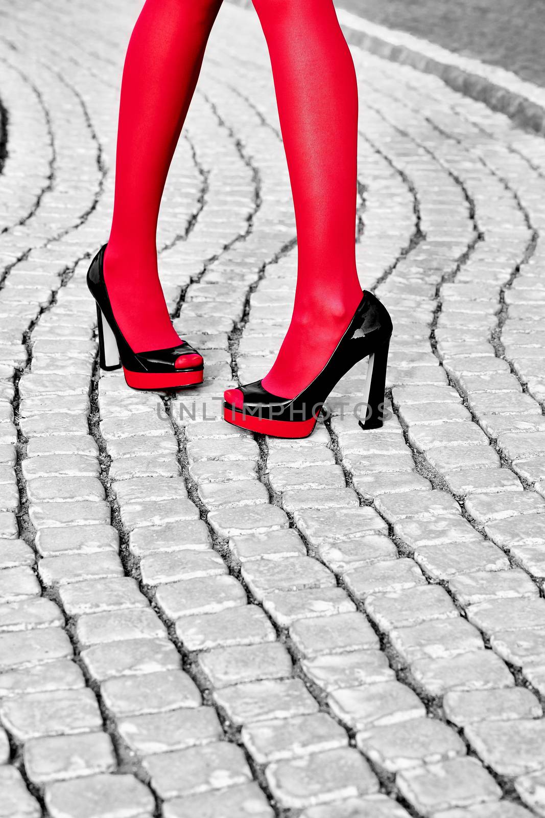 Fashion urban womens legs, red pantyhose, stylish shiny heels. Geometry square pattern, outdoor. Trendy shoes, Black and white, paving stone 