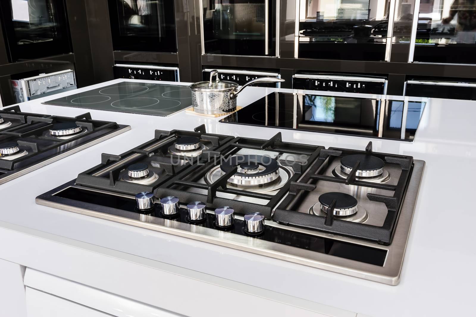 Rows of gas stoves with stainless tray selling in appliance retail store
