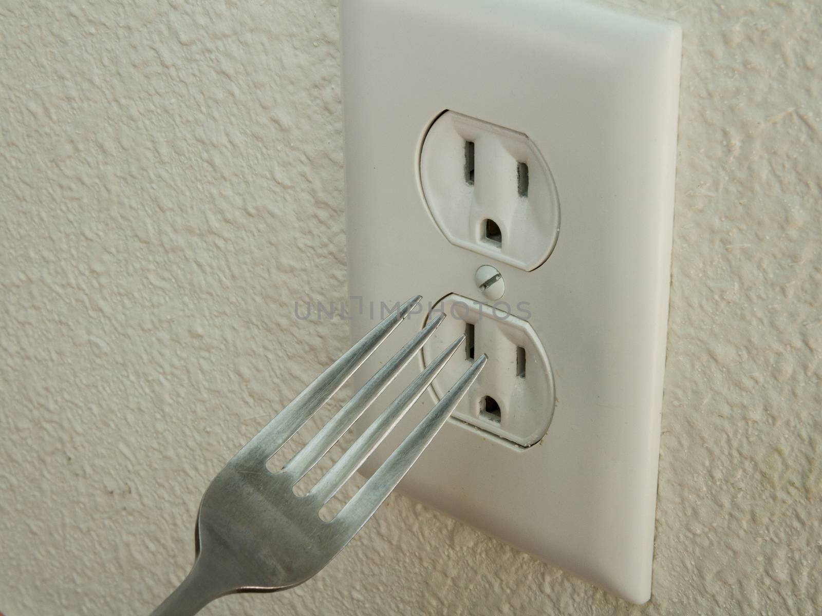 Kid trying to put a metal fork into an electrical outlet