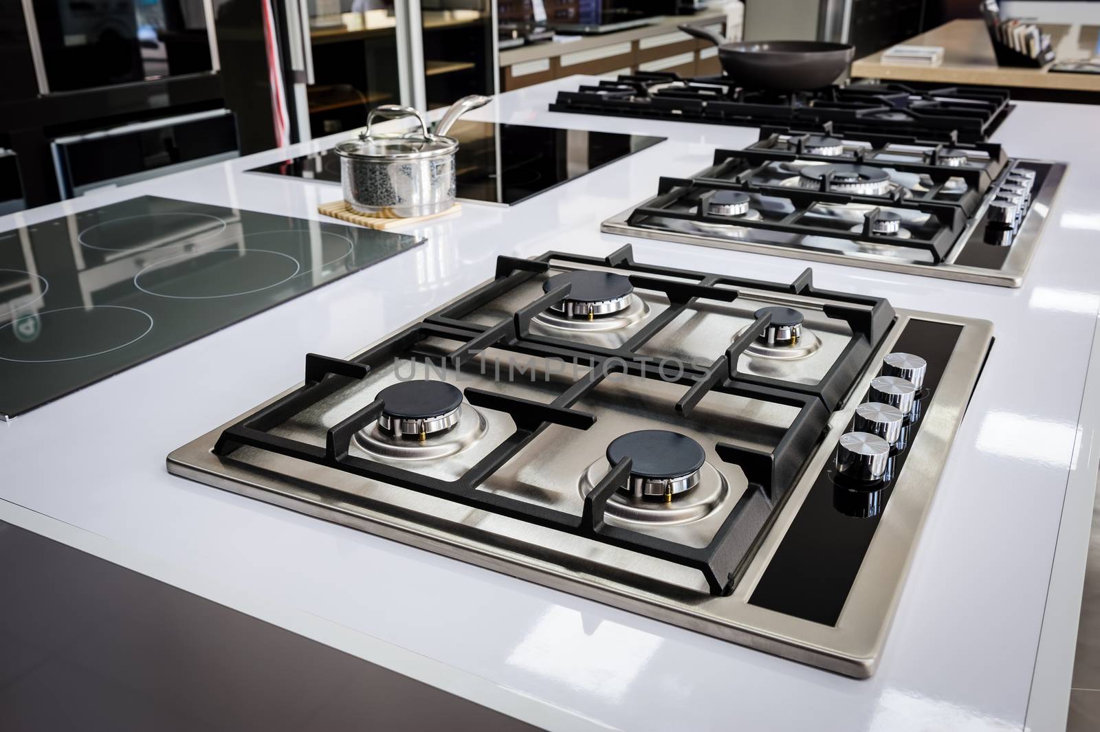 Rows of gas stoves with stainless tray selling in appliance retail store
