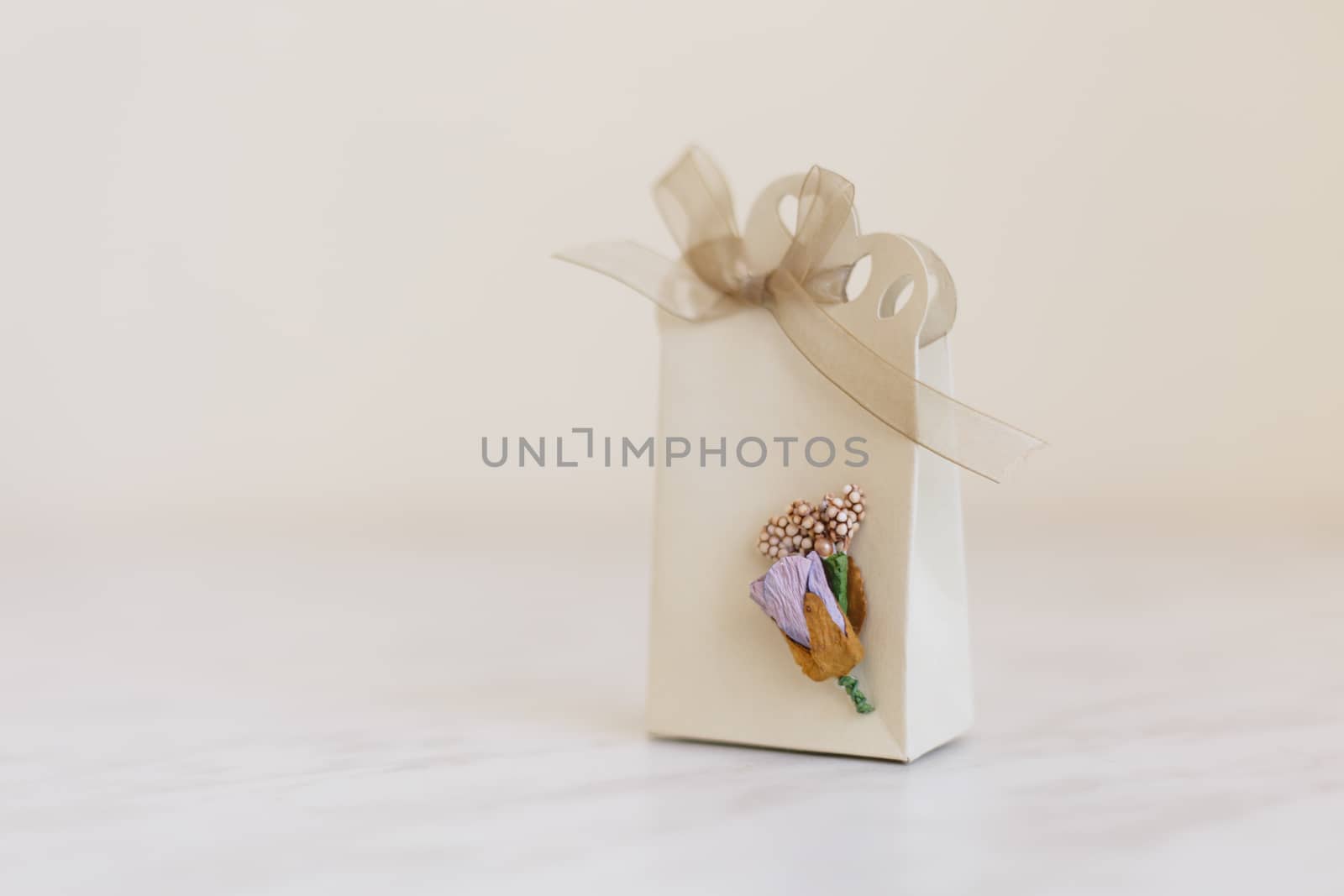 Close up detailed front view of hand-crafted white gift box with small flowers and colorful ribbons.