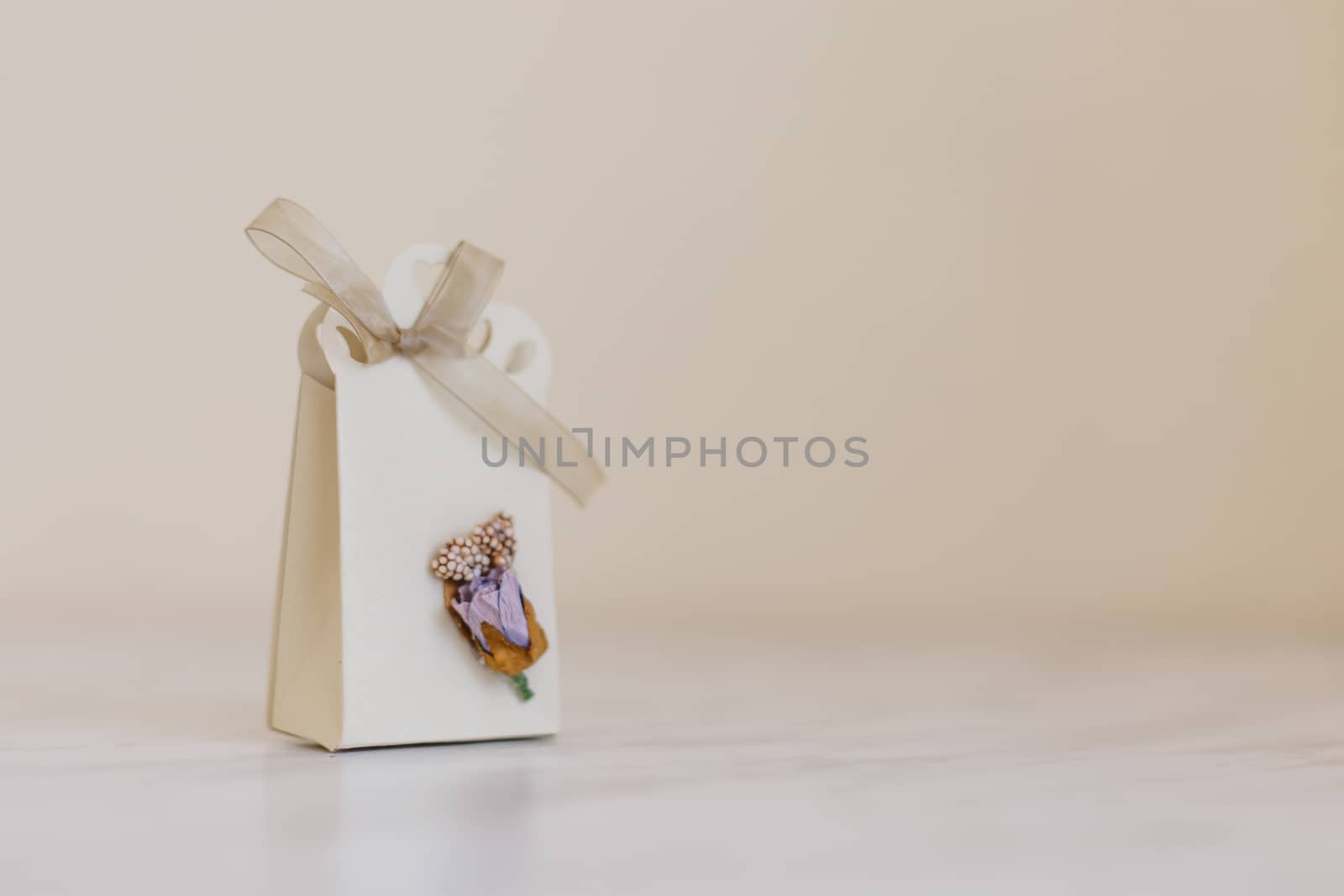 Close up detailed front view of hand-crafted white gift box with small flowers and colorful ribbons.