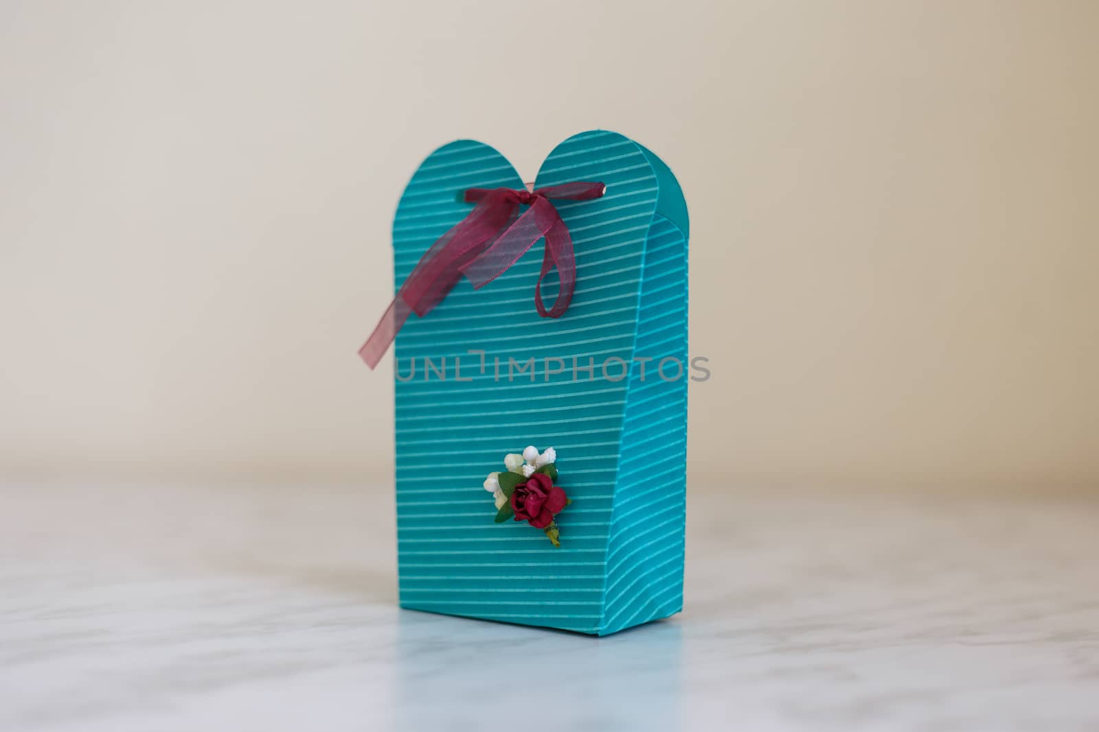 Close up detailed front view of hand-crafted green gift box with small flowers and colorful ribbons.