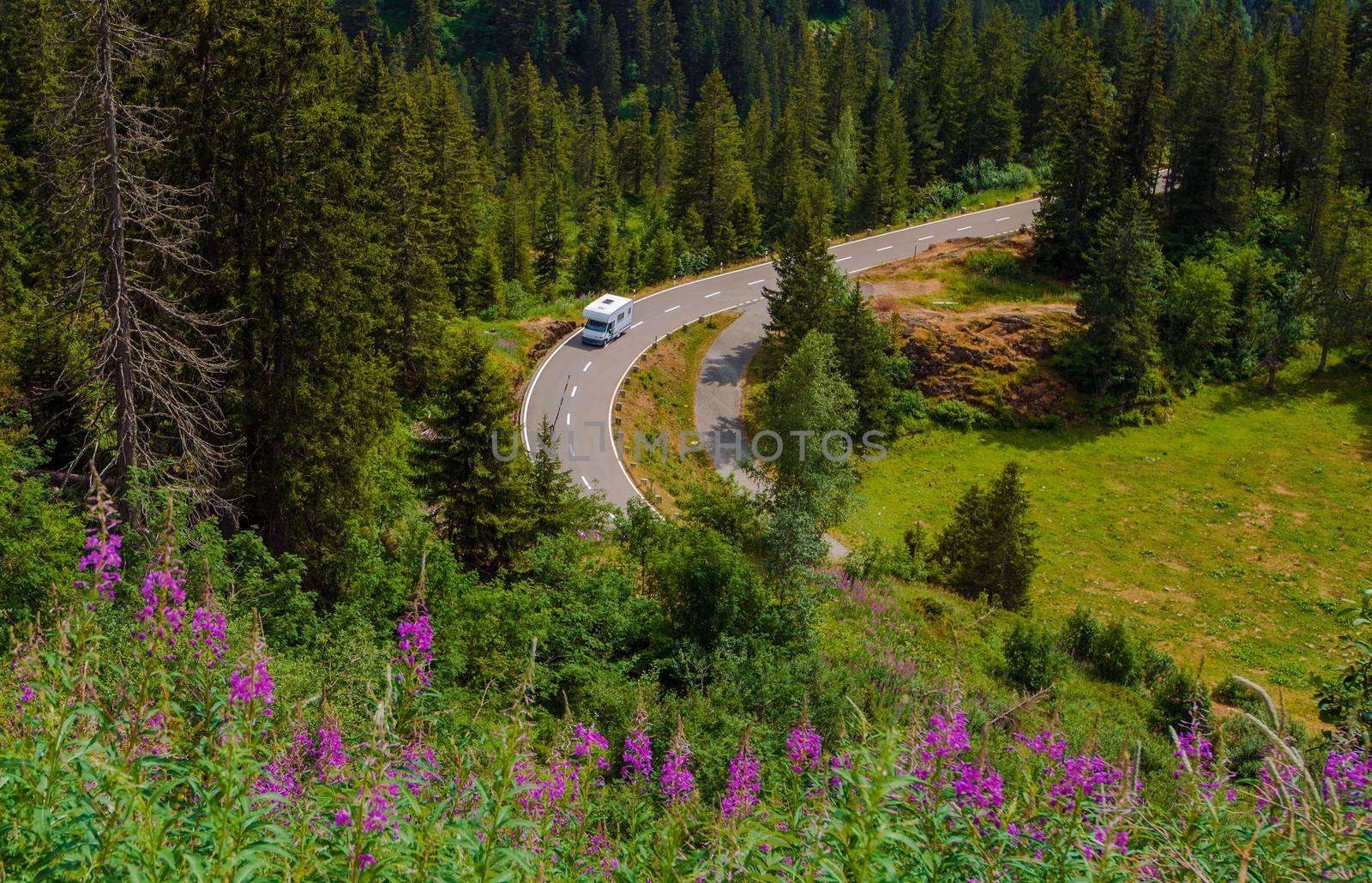 Camper Van Summer Travel. Rving Photo Theme. Small Class C Travel Camper on a Mountain Road During Summer Time.
