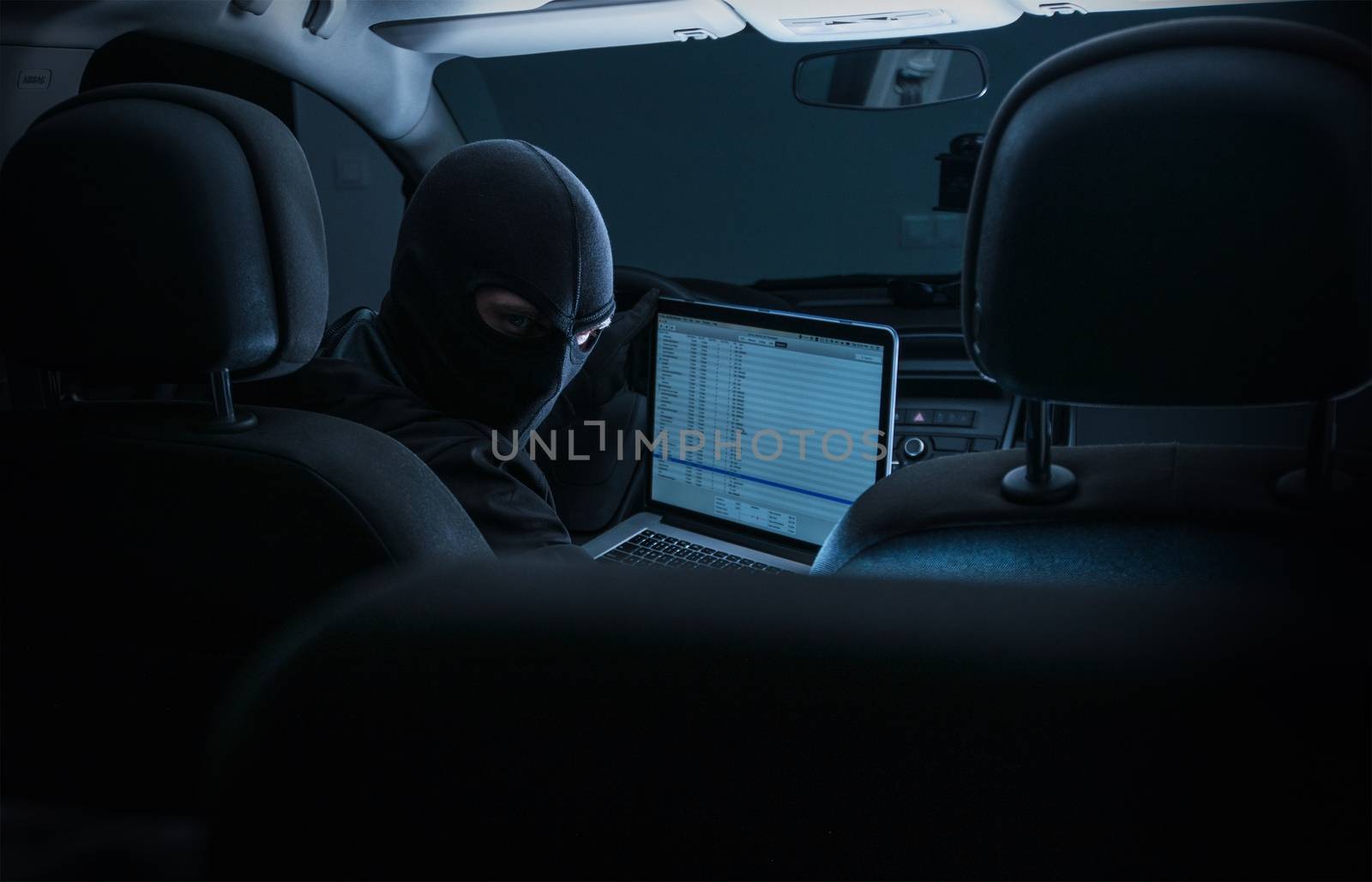 Hacking Inner Car Systems. Car Robber with Laptop Trying to Hack Modern Car System While Seating Inside the Car. 