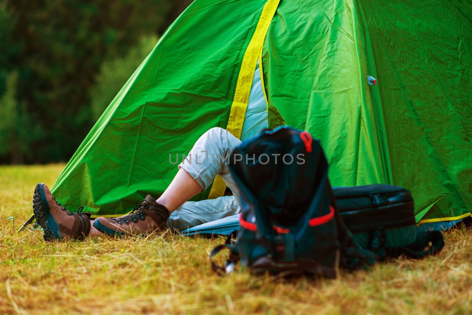 Resting Hiker in His Medium Size Tent. Wild Campsite. Hiking and Tent Camping Theme.