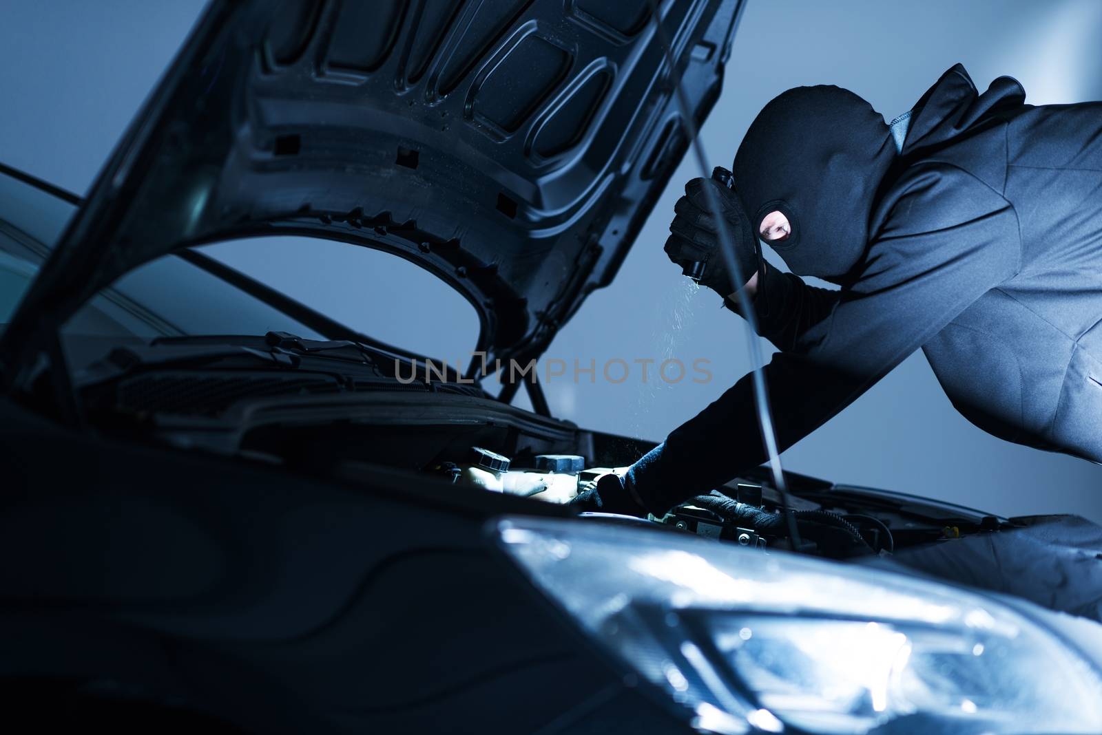Robber Disabling Car Alarm. Car Robber Looking To Disarm Car Security Systems Under the Car Hood. 