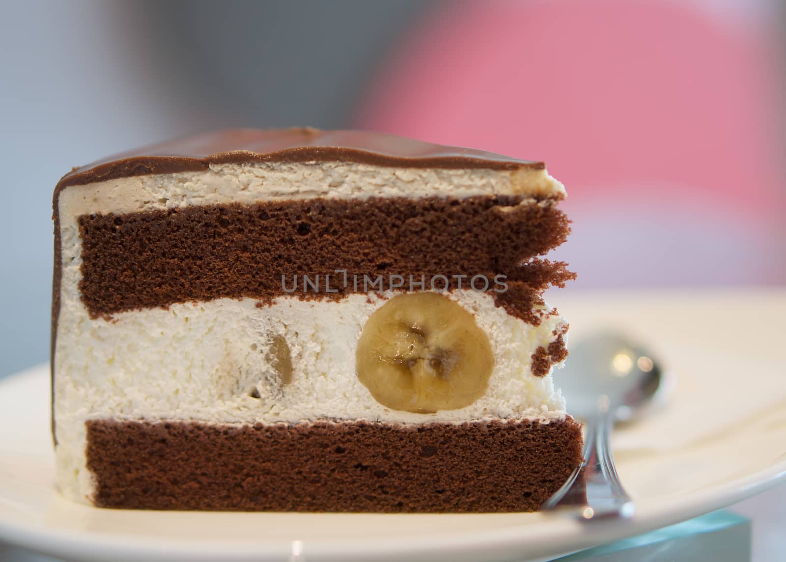 Delicious banana chocolate cake on white plate on table in restaurant.