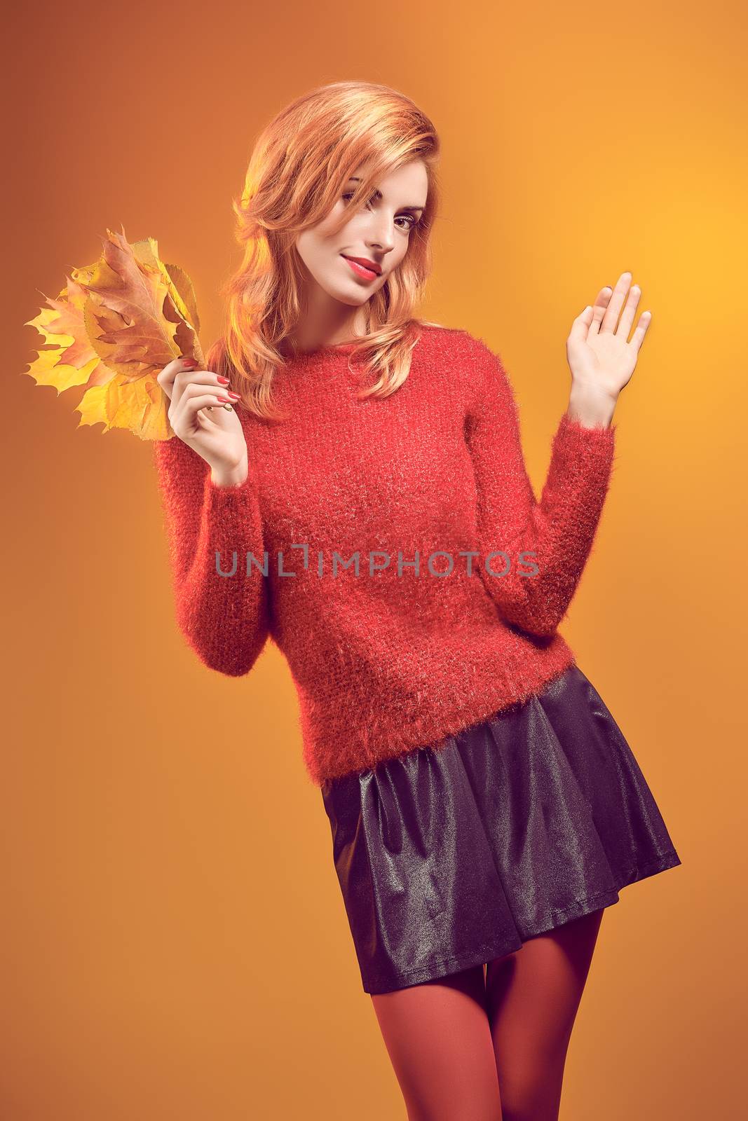 Beauty portrait redhead young model woman, autumn leafs in hands. Attractive happy playful girl in stylish red sweater, people. Retro, vintage, creative toned.Orange yellow background,copyspace
