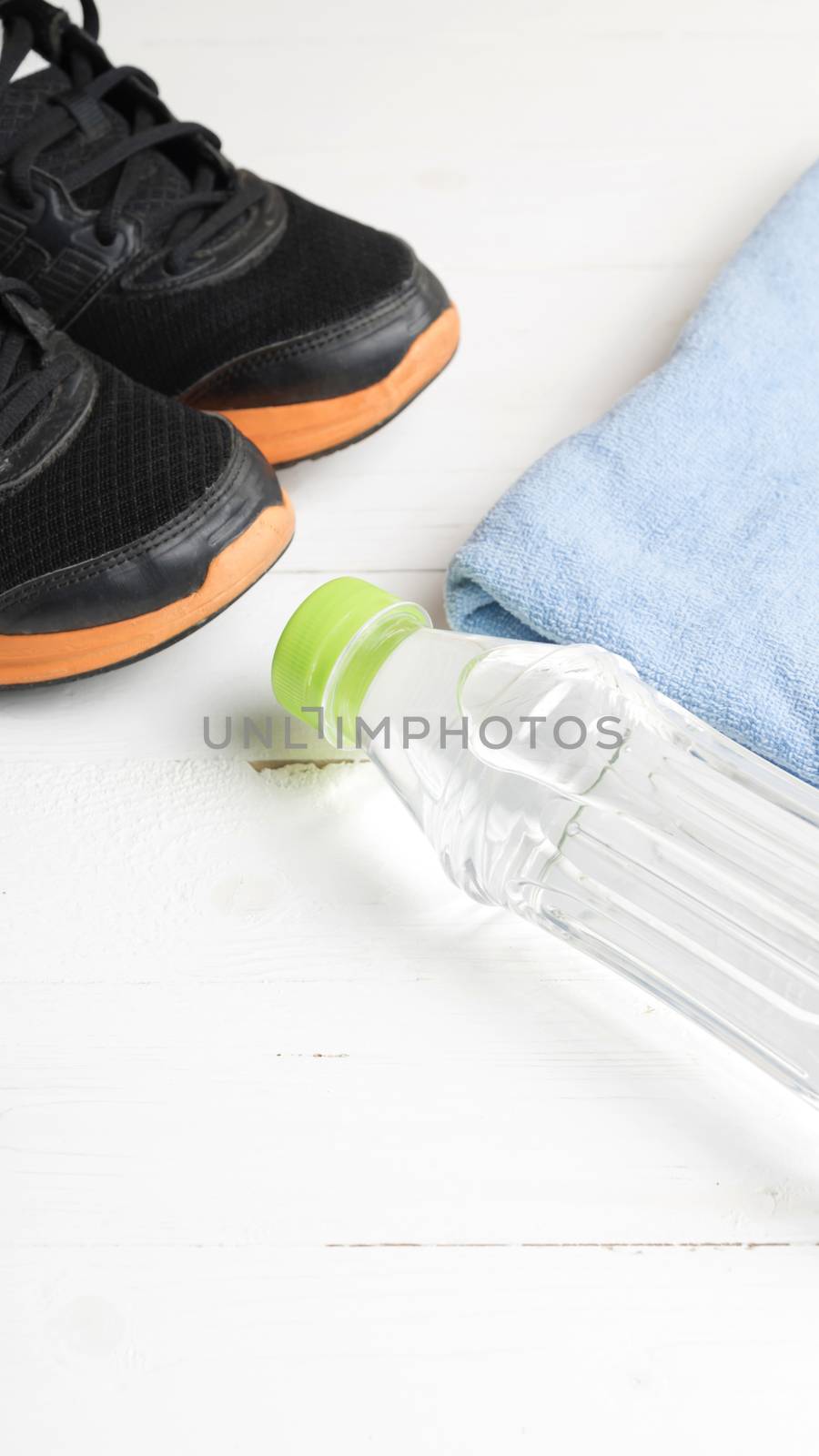 fitness equipment:blue towel,drinking water and running shoes on white wood table