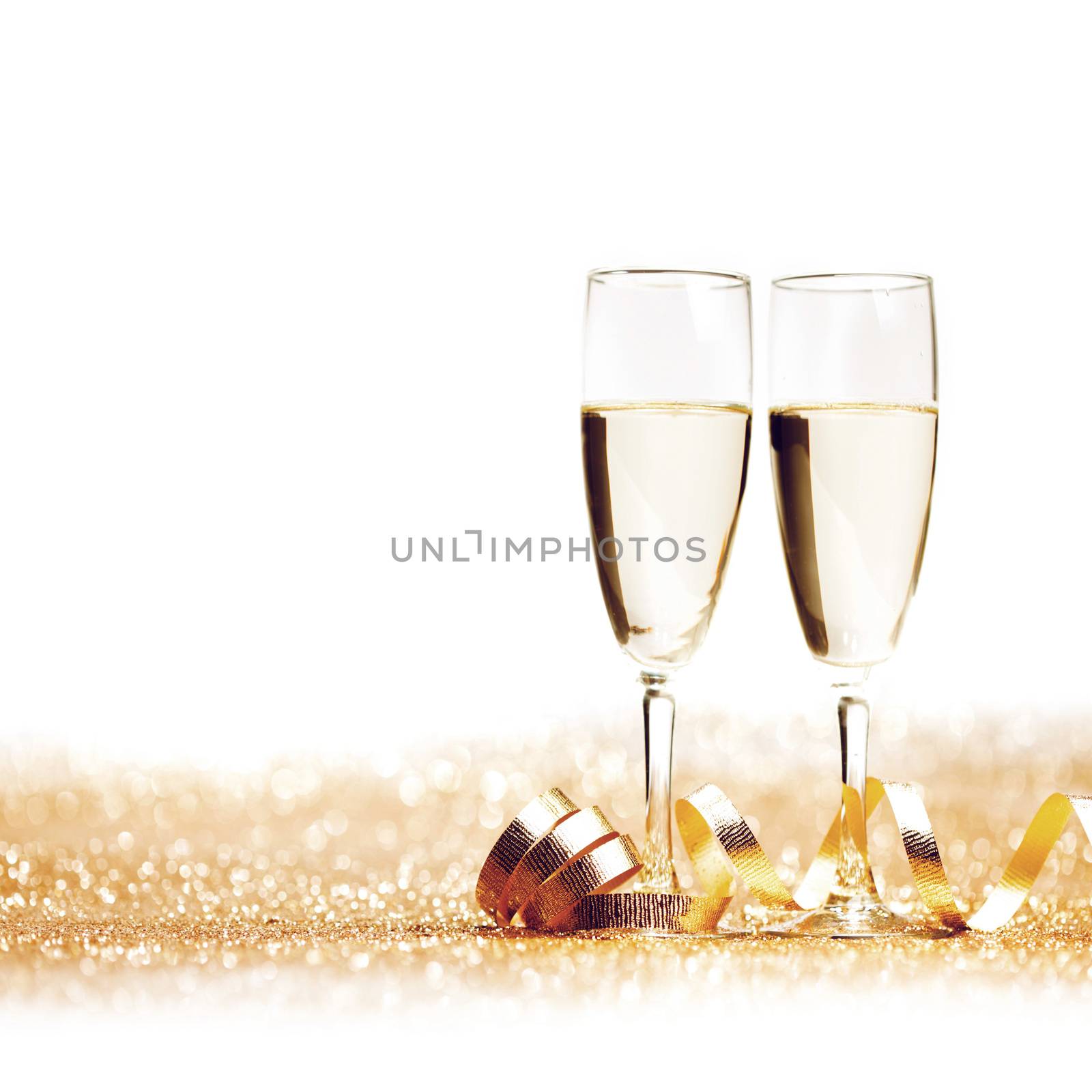 Glasses of champagne and decorative golden ribbon isolated on white