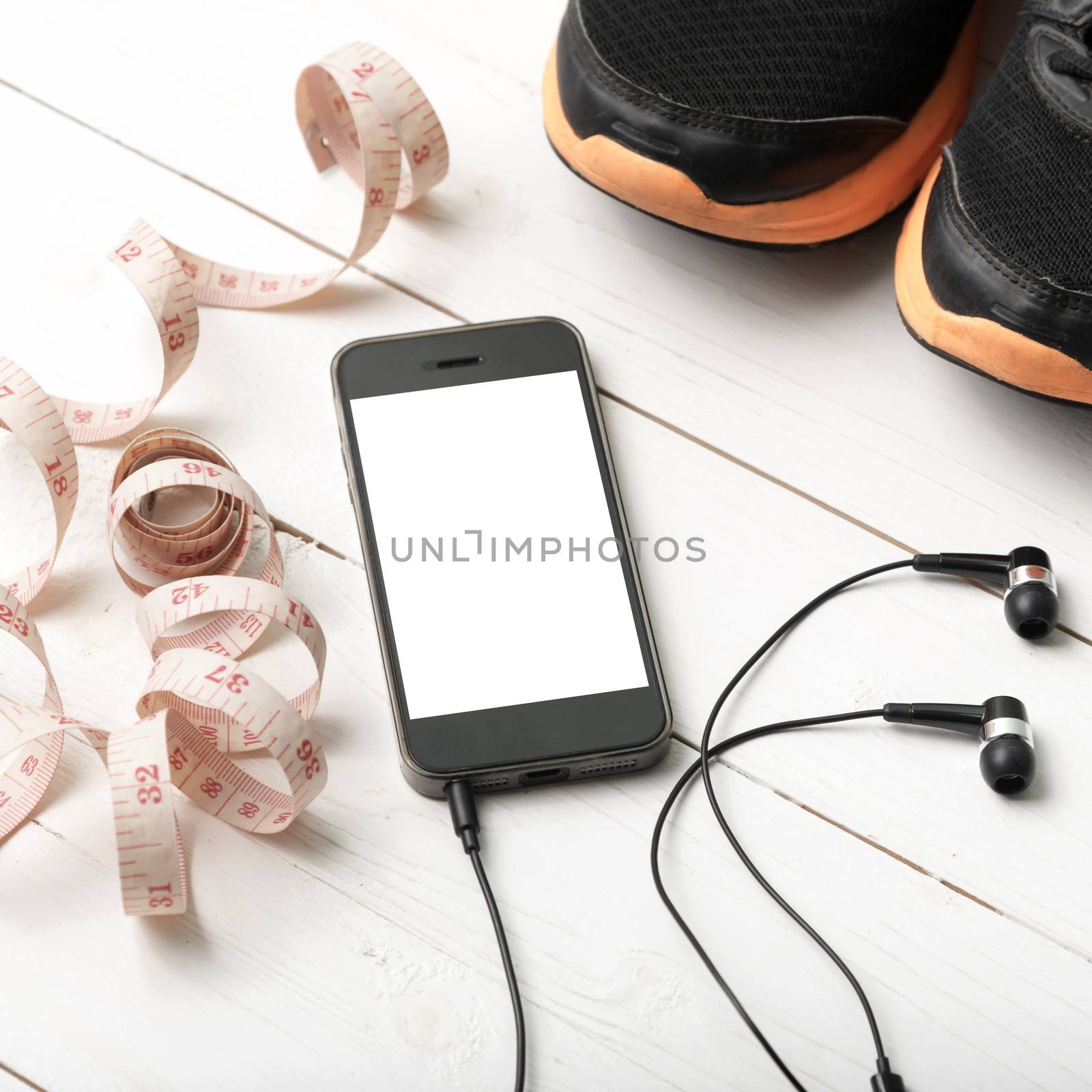 running shoes,measuring tape and phone on white wood table