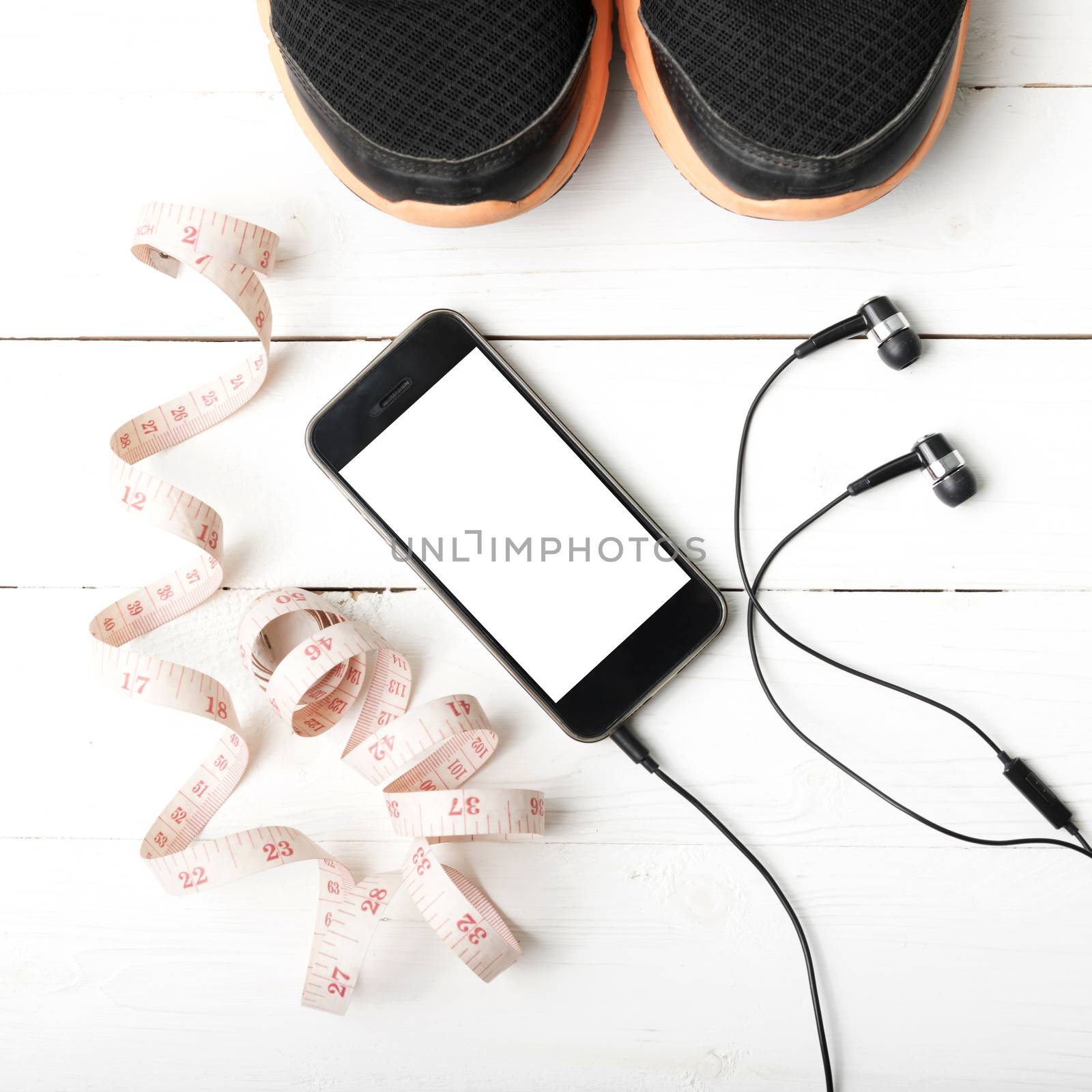 running shoes,measuring tape and phone on white wood table