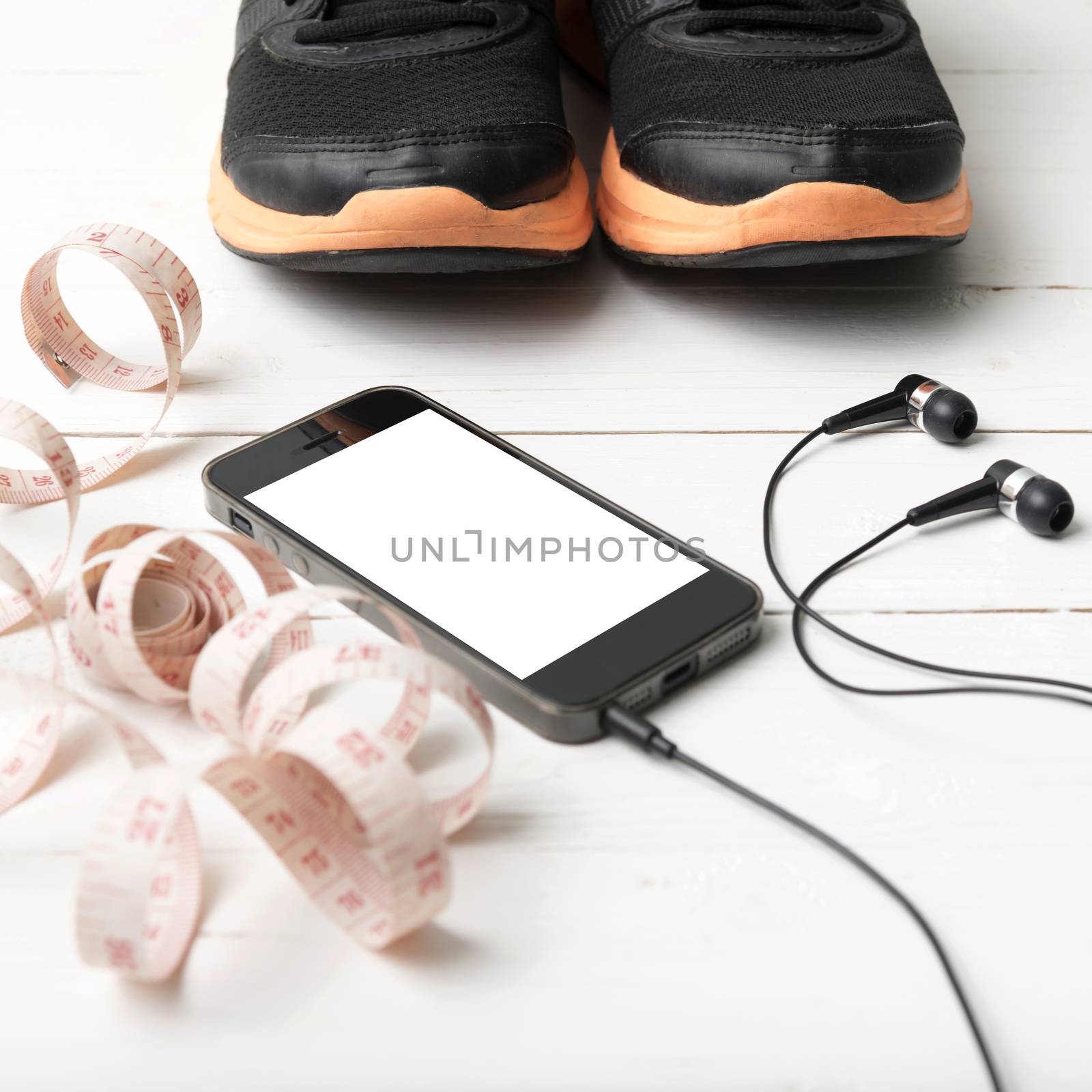 running shoes,measuring tape and phone on white wood table