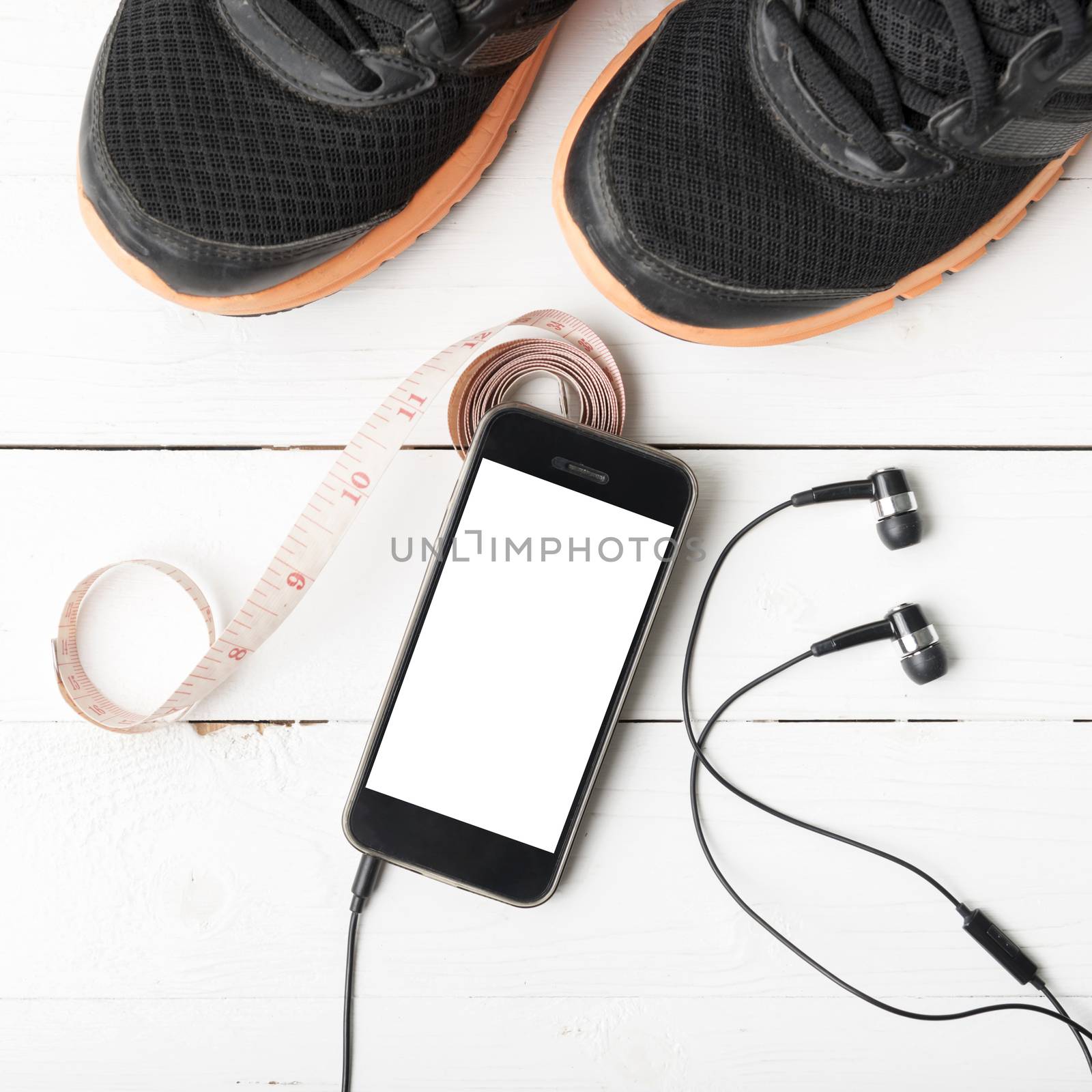 running shoes,measuring tape and phone on white wood table