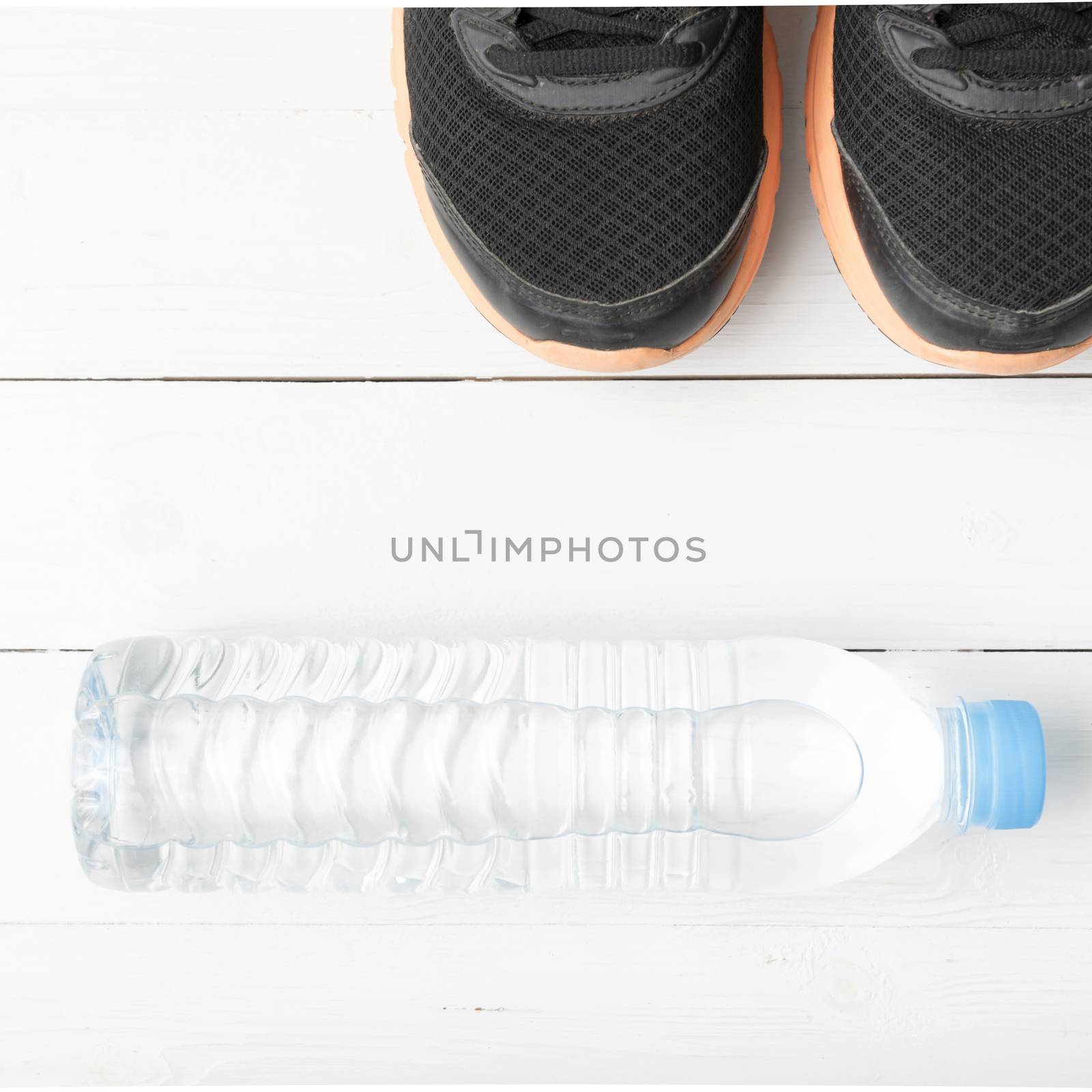 running shoes and drinking water on white table