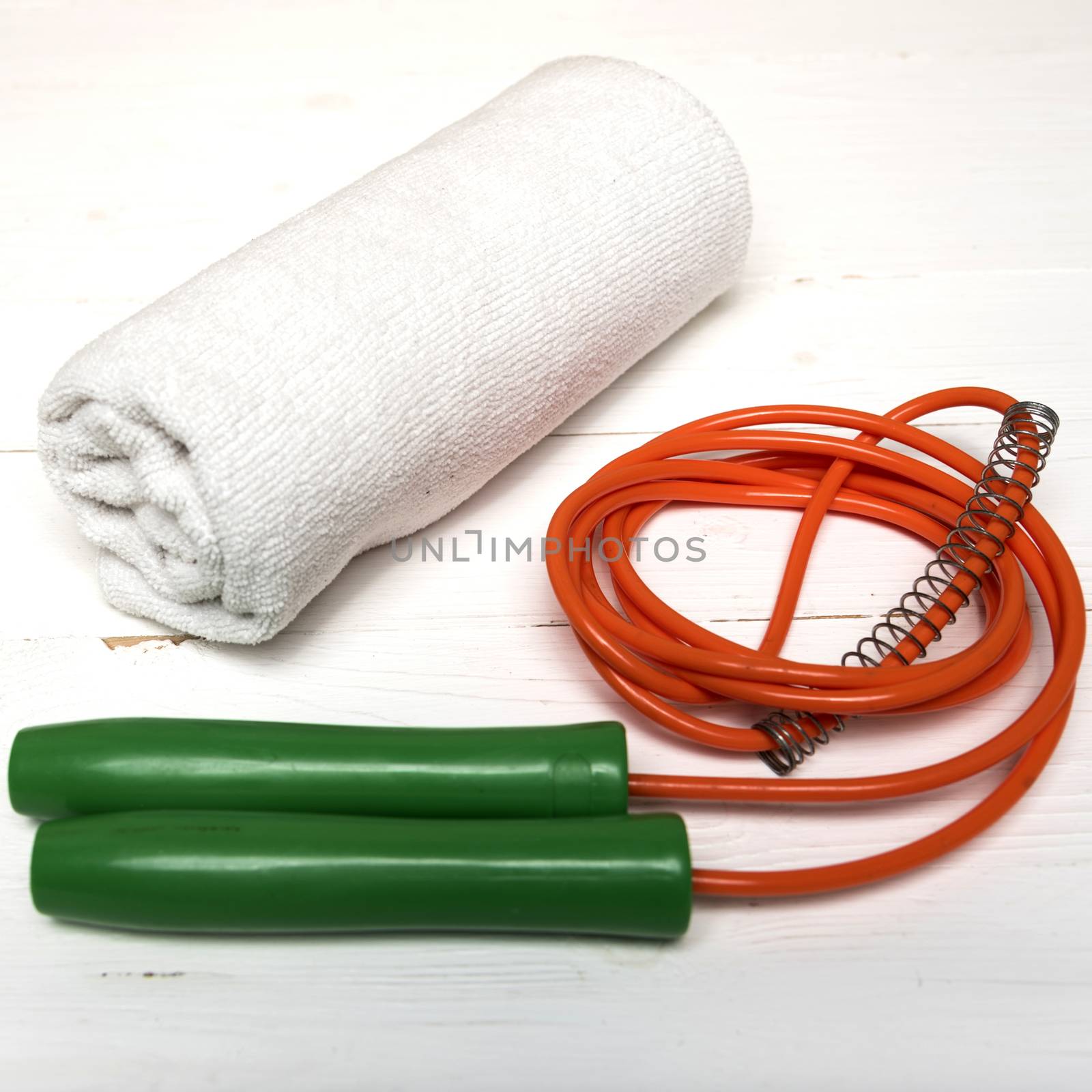 fitness equipment:white towel,jumping rope on white wood table