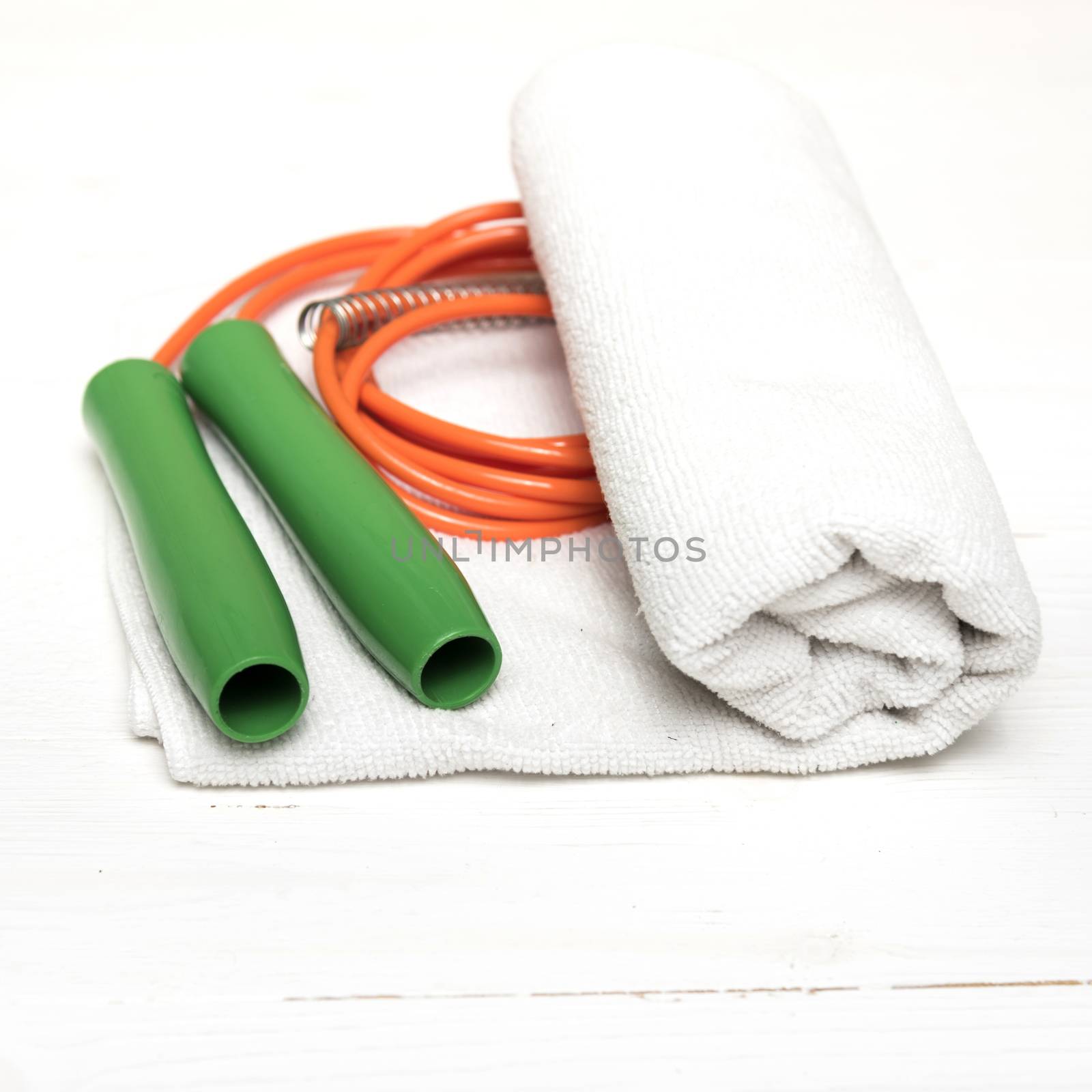 fitness equipment:white towel,jumping rope on white wood table